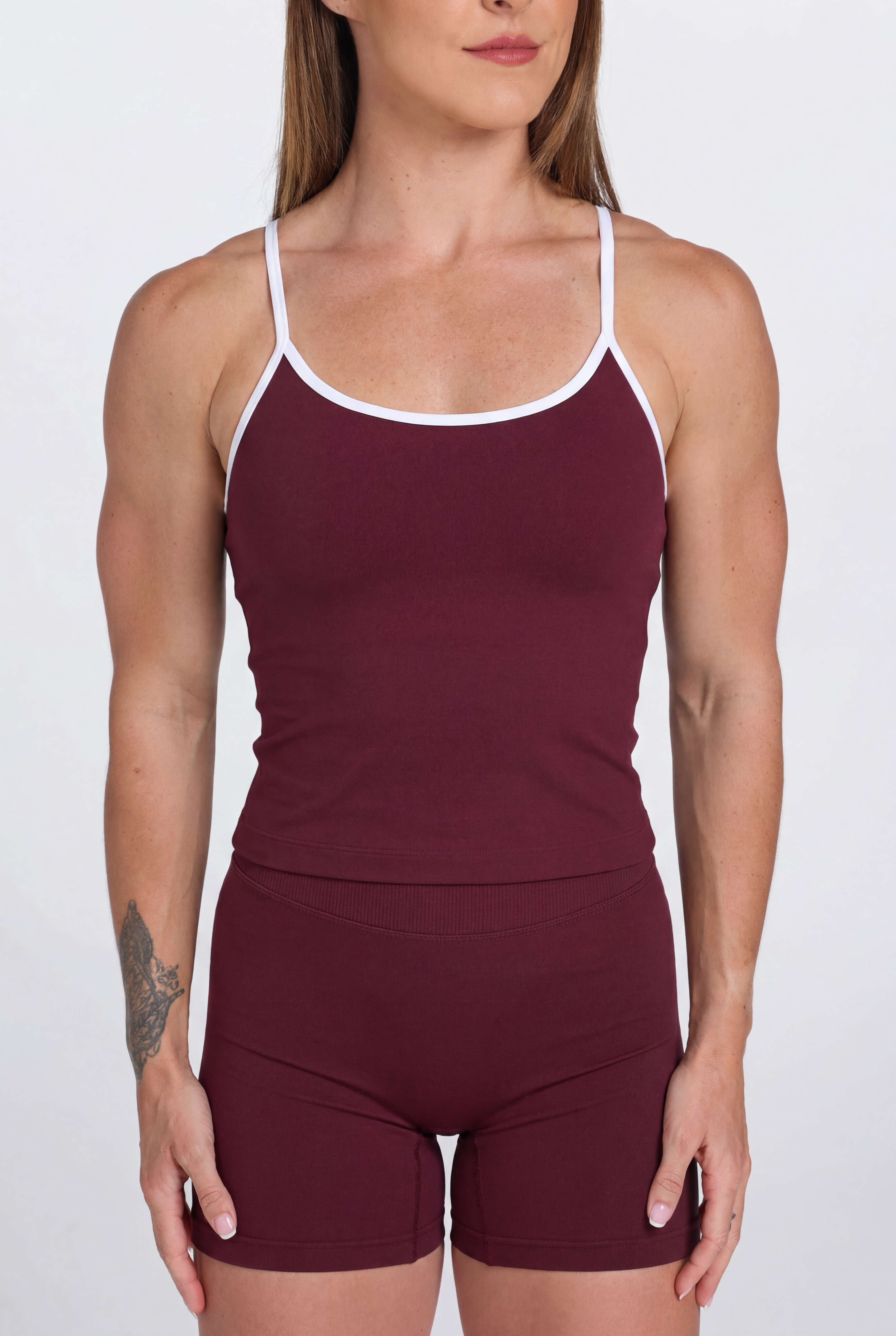 Woman wearing a wine tank top and shorts set with white trim on a white background