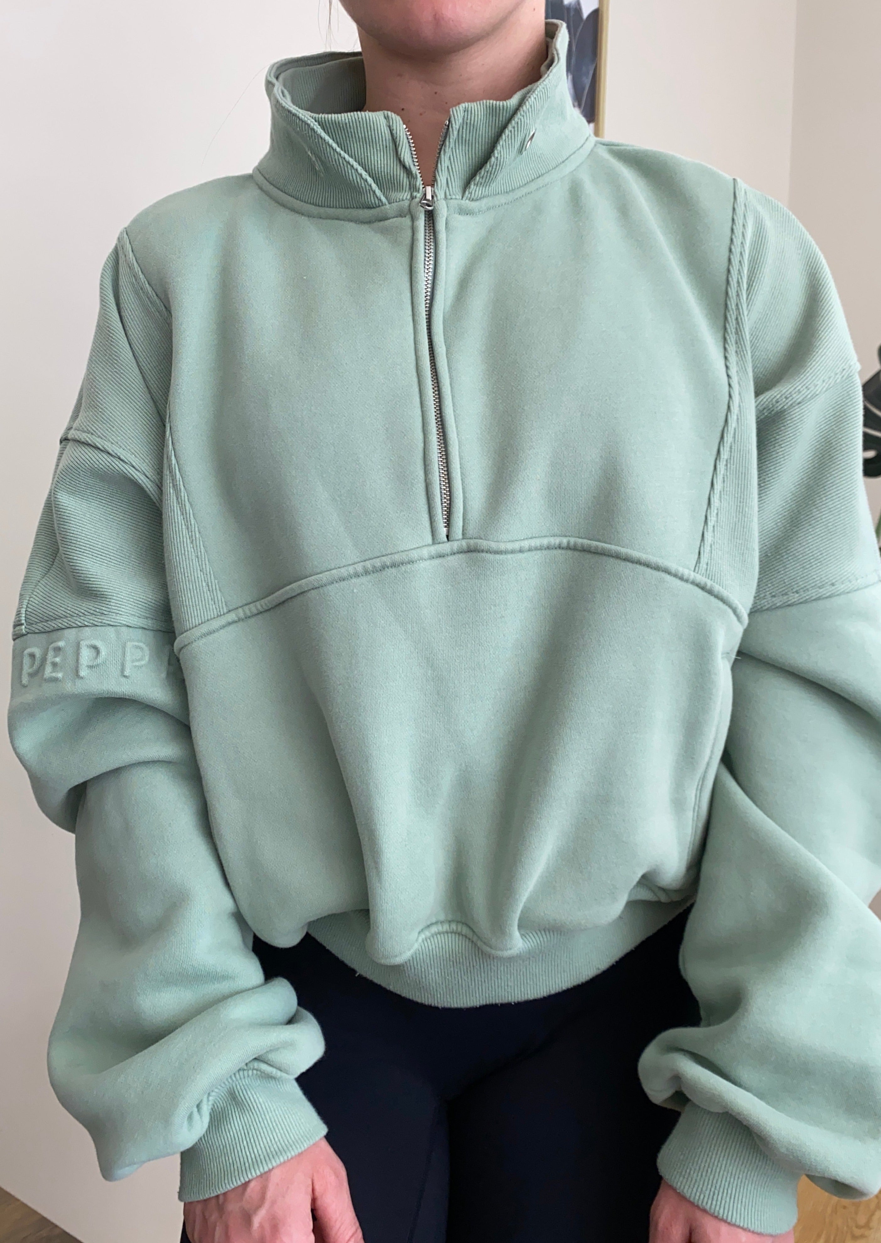 Fleece lined crop jacket in light green with half zip, and ribbed panels, and side pockets.