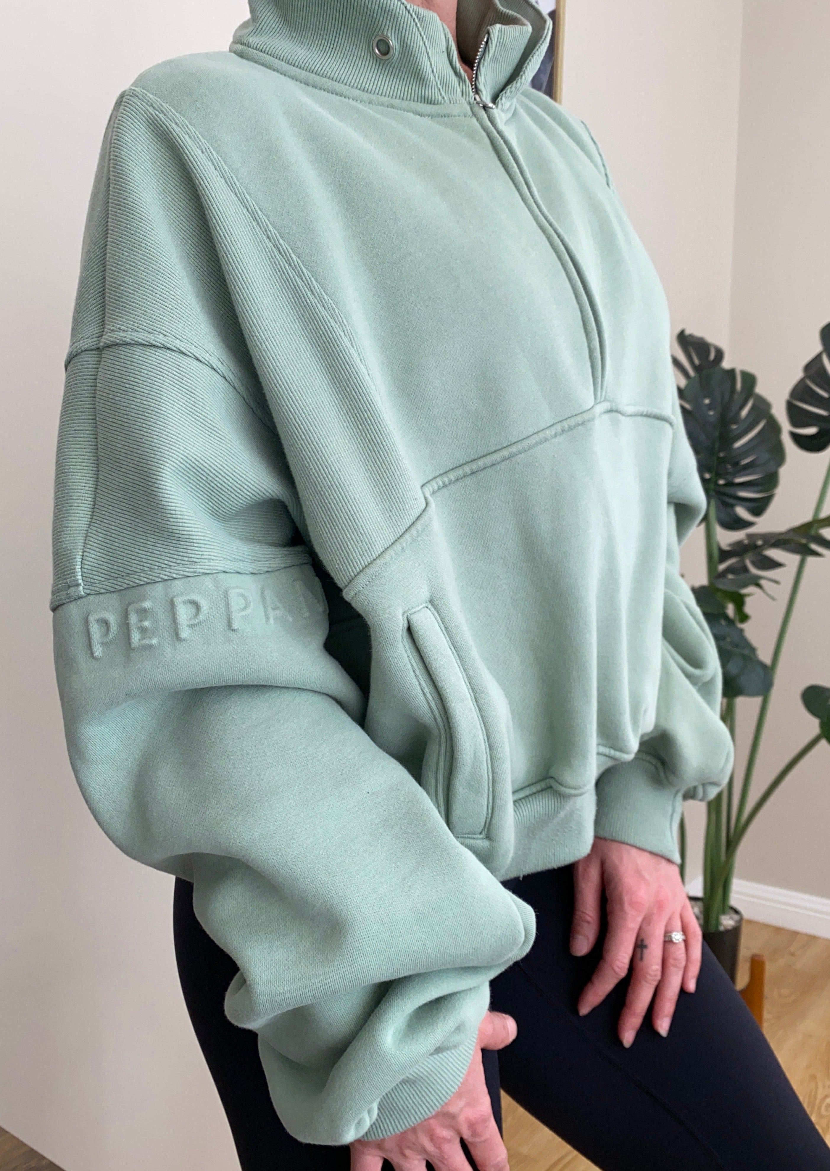 Fleece lined crop jacket in light green with half zip, and ribbed panels, and side pockets.