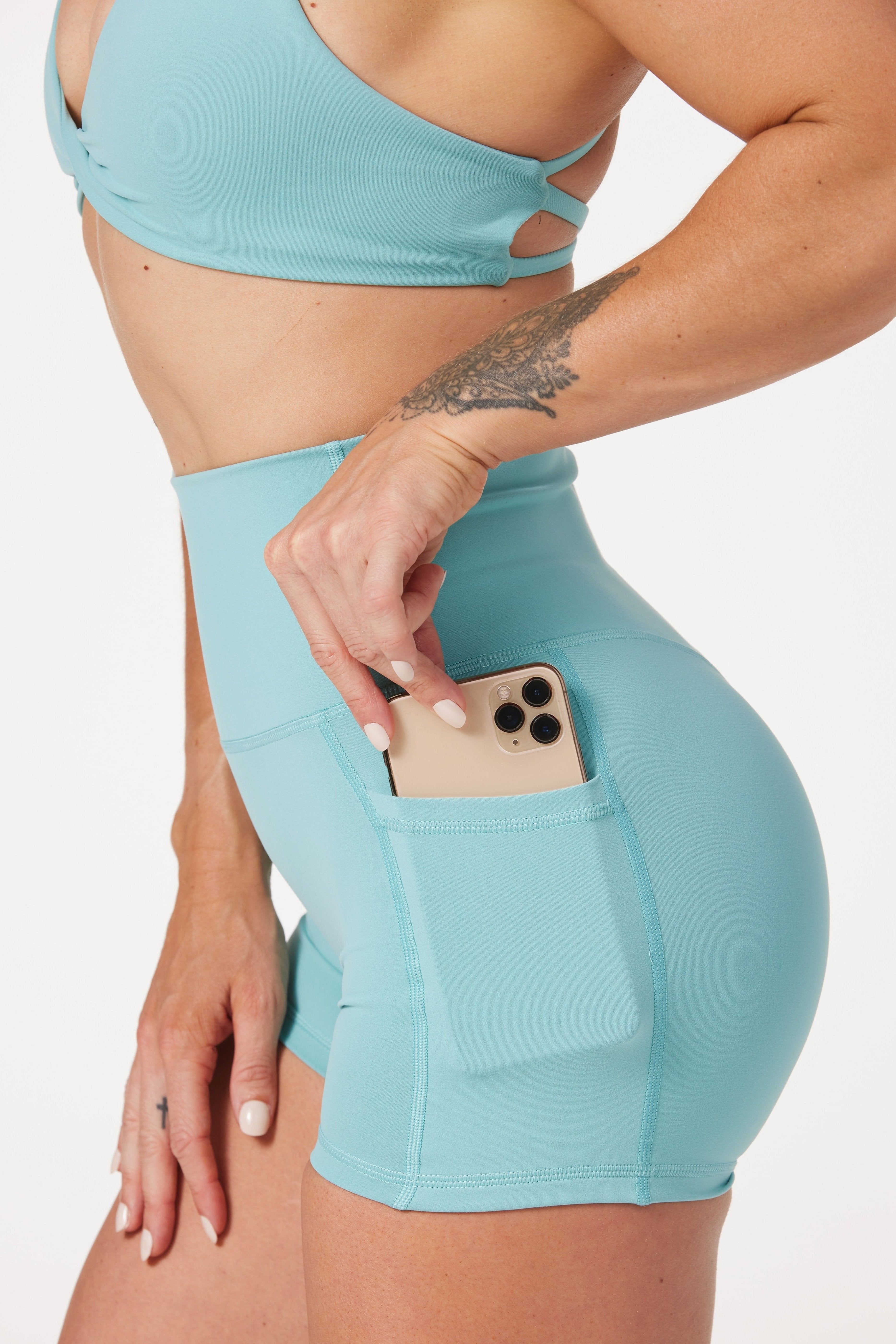 high waisted 4" inseam activewear pockets shorts with no front rise seam, in a buttery soft, supportive fabric with twist bra and cross over straps in lagoon green