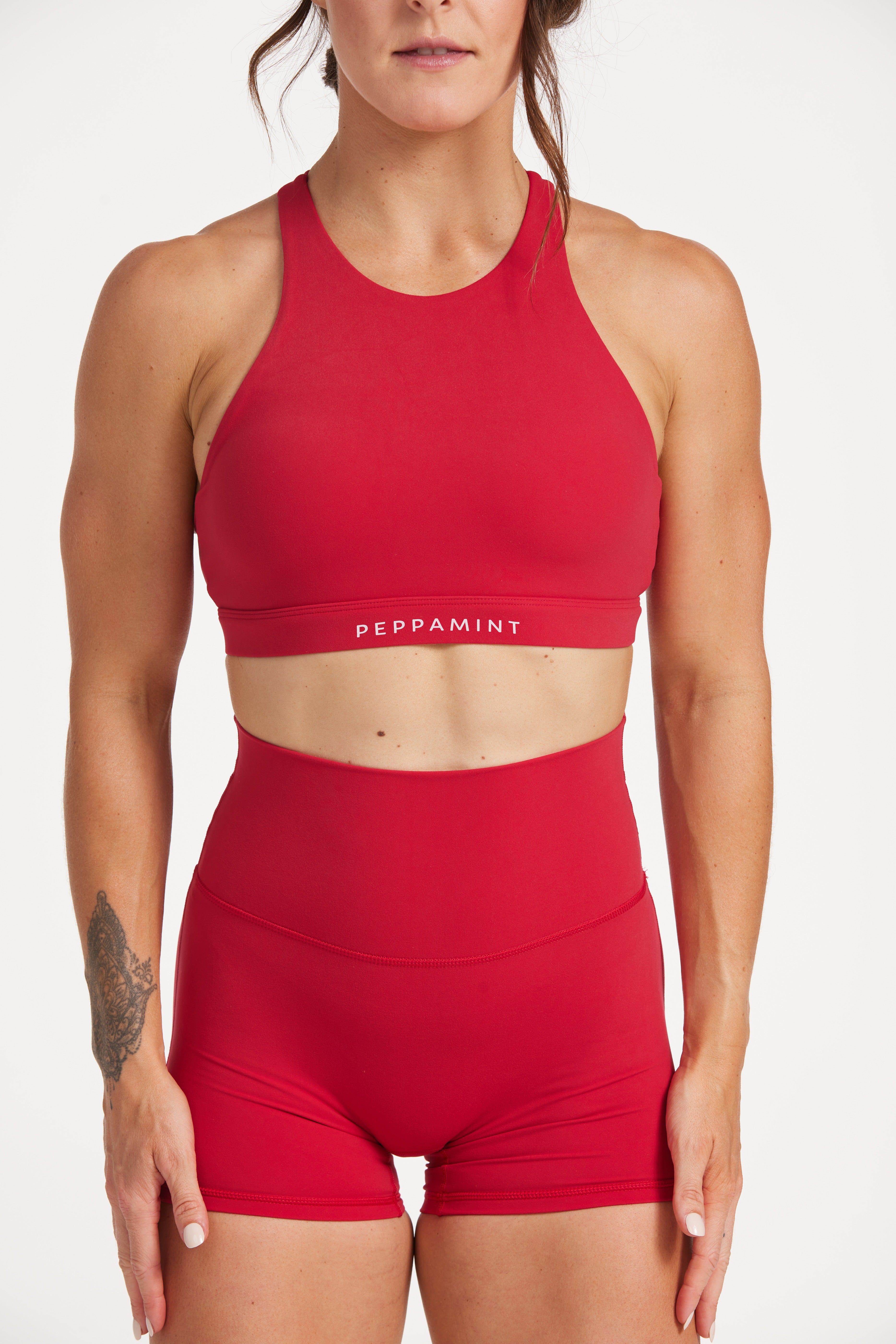 Buttery soft high waisted women's gym shorts with 4" inseam with curved stitched detailing for a butt shaping effect, and no front rise seam, paired with a high neck women's sports bra with a supportive elasticated hem and triple layered fabric with removable pads for extra support and crossover back straps in Raspberry red.
