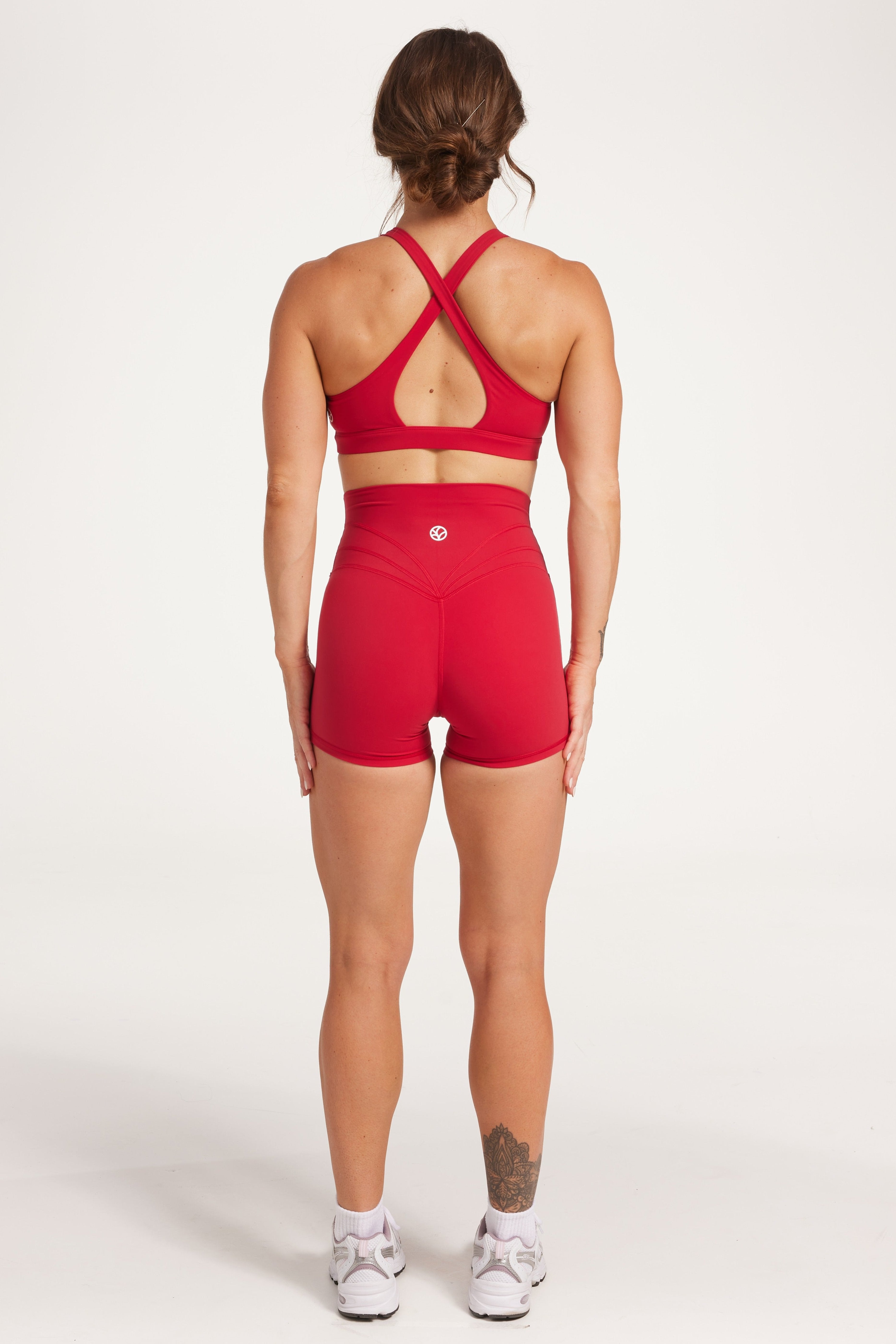 Buttery soft high waisted women's gym shorts with 4" inseam with curved stitched detailing for a butt shaping effect, and no front rise seam, paired with a high neck women's sports bra with a supportive elasticated hem and triple layered fabric with removable pads for extra support and crossover back straps in Raspberry red.