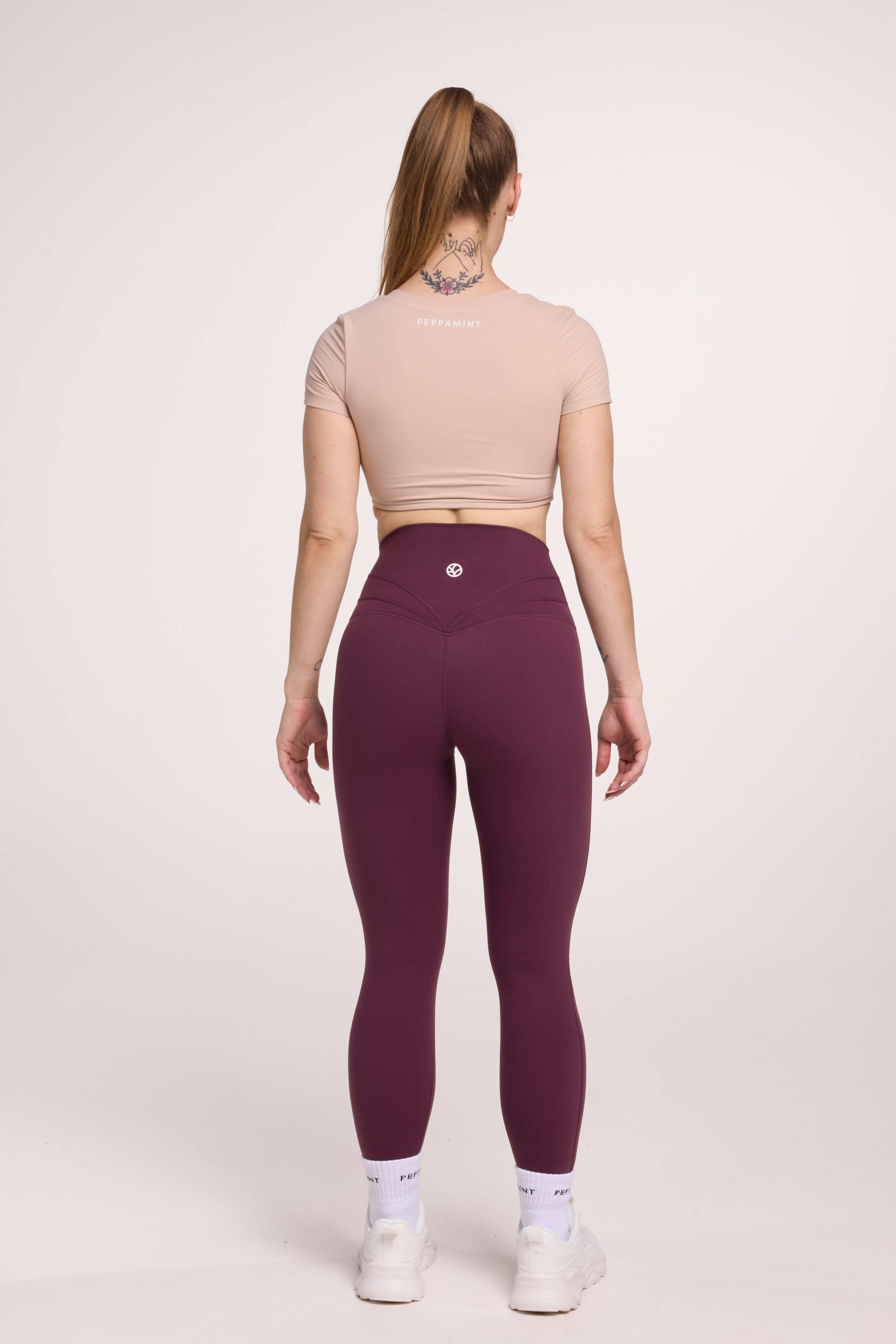 Buttery soft high waisted women's gym tights with curved back seam stitched detailing for a butt shaping effect, and no front rise seam, in plum purple paired with an V neck women's crop t-shirt with a supportive elasticated hem and triple layered fabric with removable pads for extra support in
beige