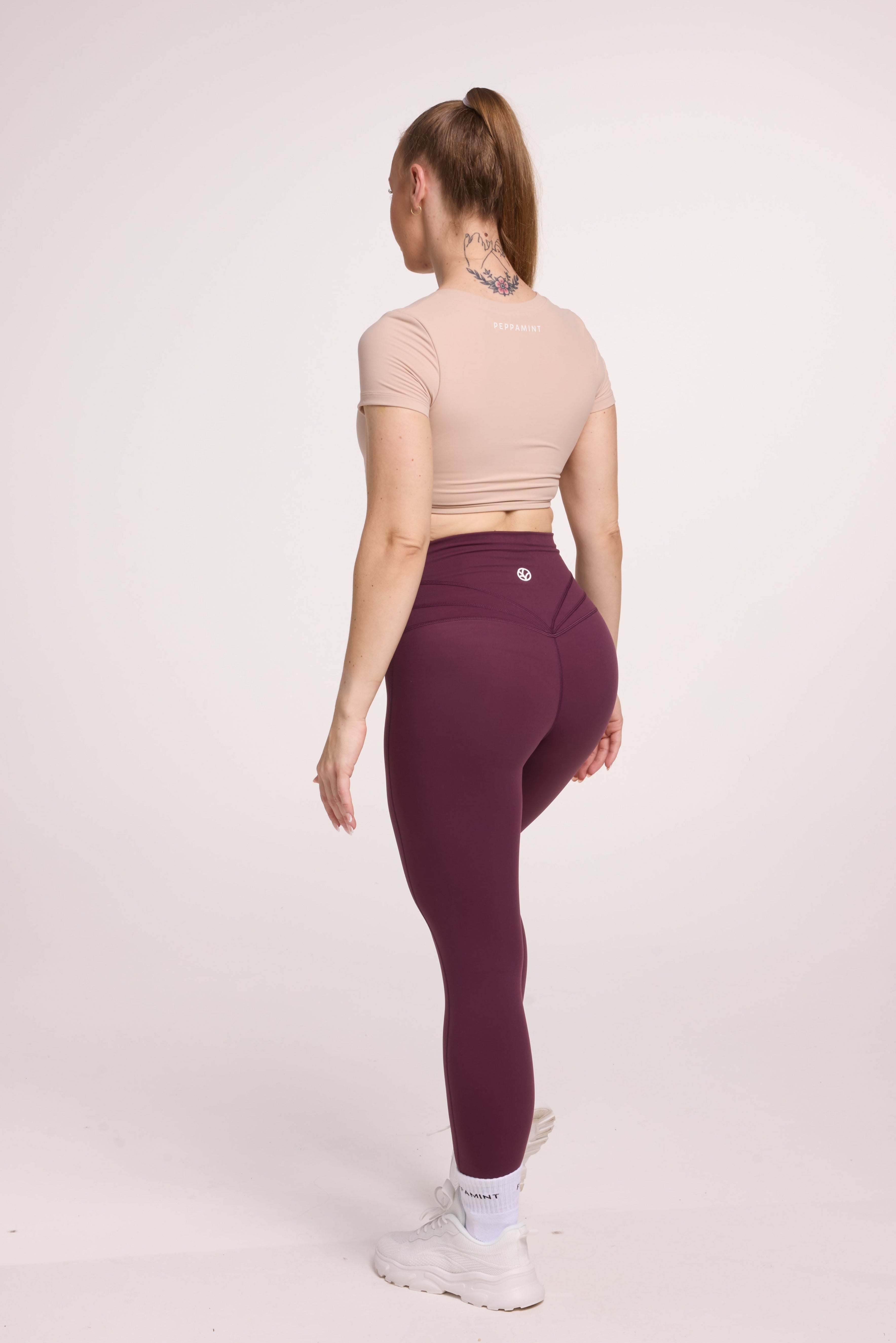 Buttery soft high waisted women's gym tights with curved back seam stitched detailing for a butt shaping effect, and no front rise seam, in plum purple paired with an V neck women's crop t-shirt with a supportive elasticated hem and triple layered fabric with removable pads for extra support in
beige