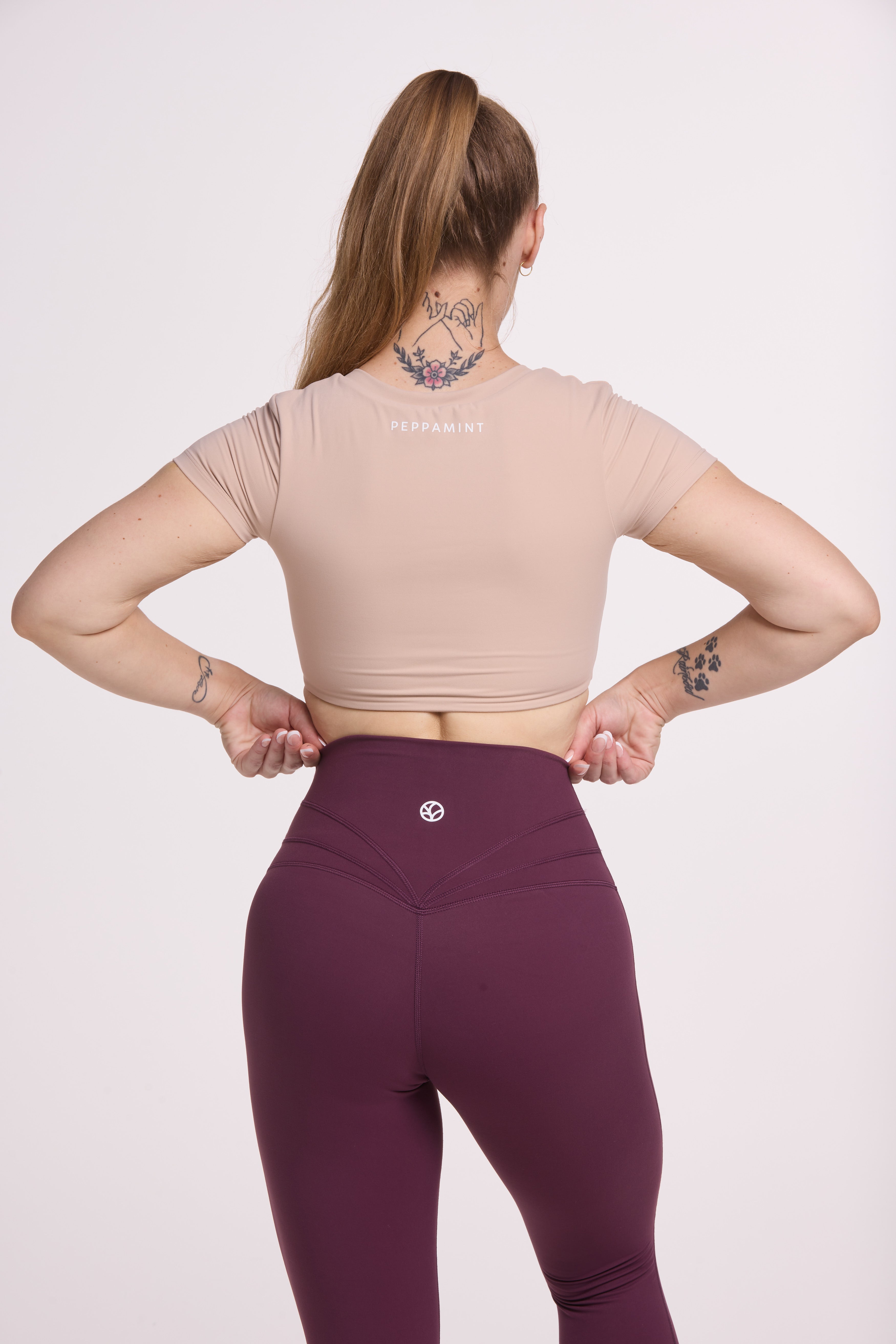 Buttery soft high waisted women's gym tights with curved back seam stitched detailing for a butt shaping effect, and no front rise seam, in plum purple paired with an V neck women's crop t-shirt with a supportive elasticated hem and triple layered fabric with removable pads for extra support in
beige