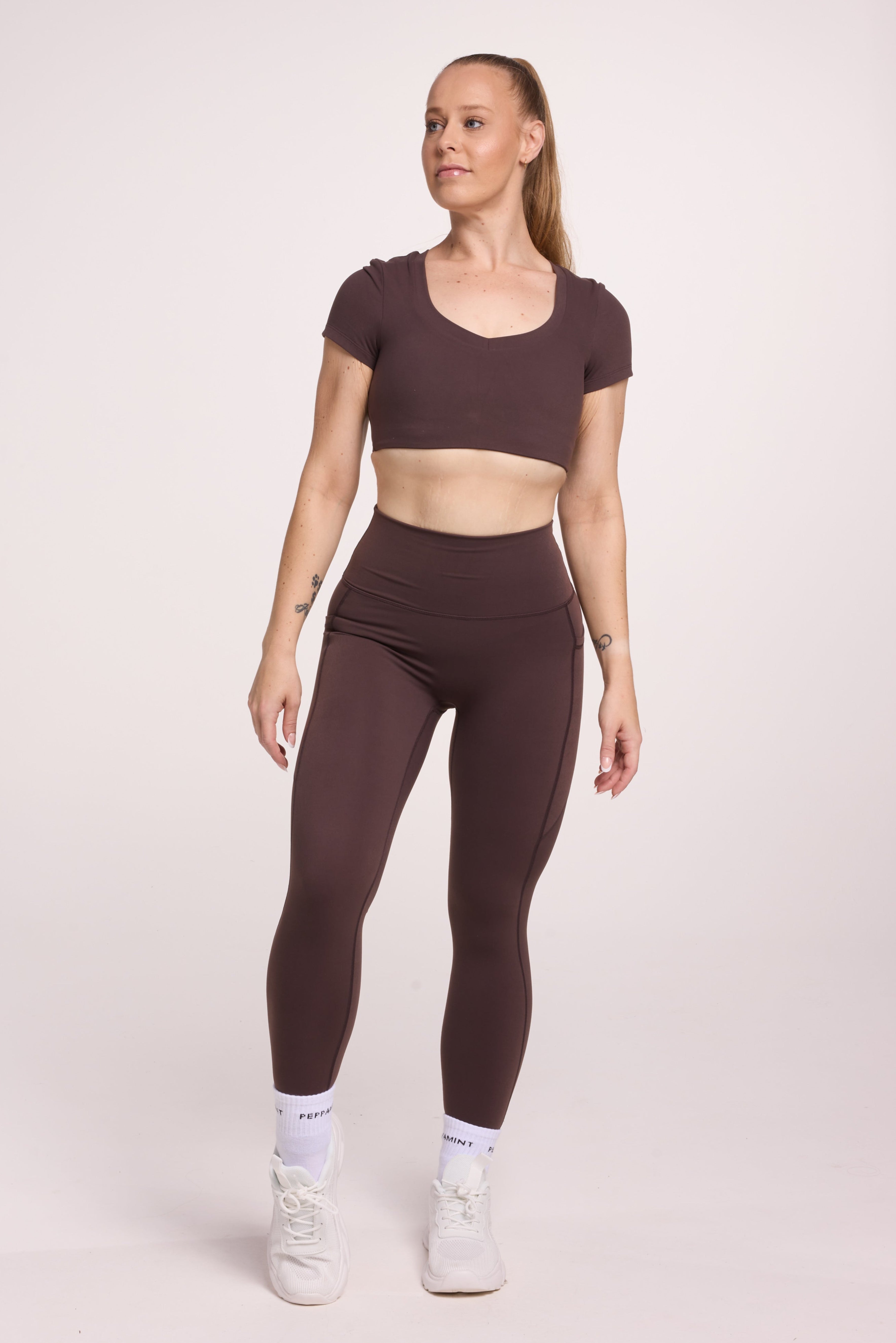 Buttery soft high waisted women's gym tights with practical pockets, sweetheart back seams for an upper glute shaping effect, and no front rise seam, paired with an V neck women's crop t-shirt with a supportive elasticated hem and triple layered fabric with removable pads for extra support in
chocolate