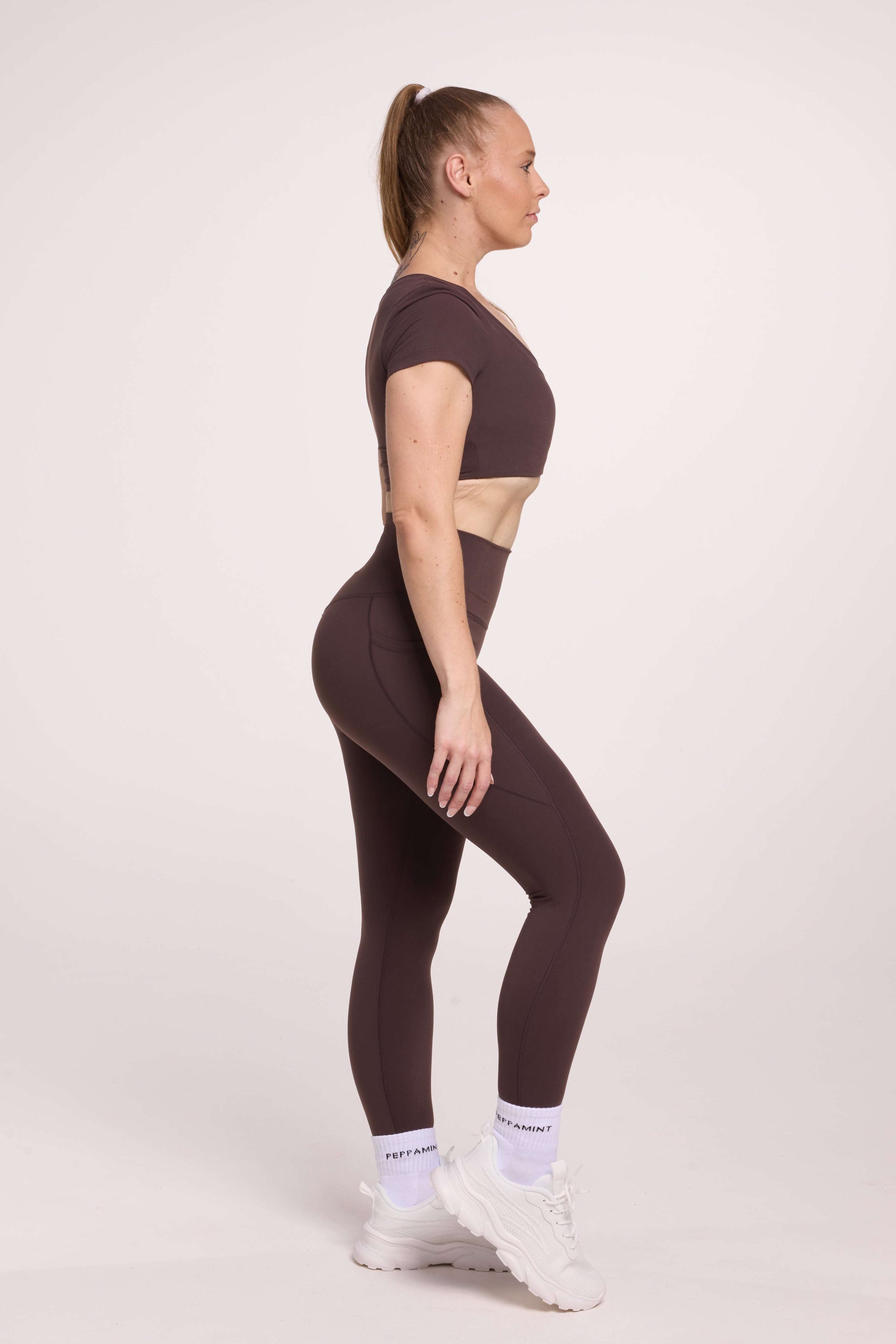 Buttery soft high waisted women's gym tights with practical pockets, sweetheart back seams for an upper glute shaping effect, and no front rise seam, paired with an V neck women's crop t-shirt with a supportive elasticated hem and triple layered fabric with removable pads for extra support in
chocolate