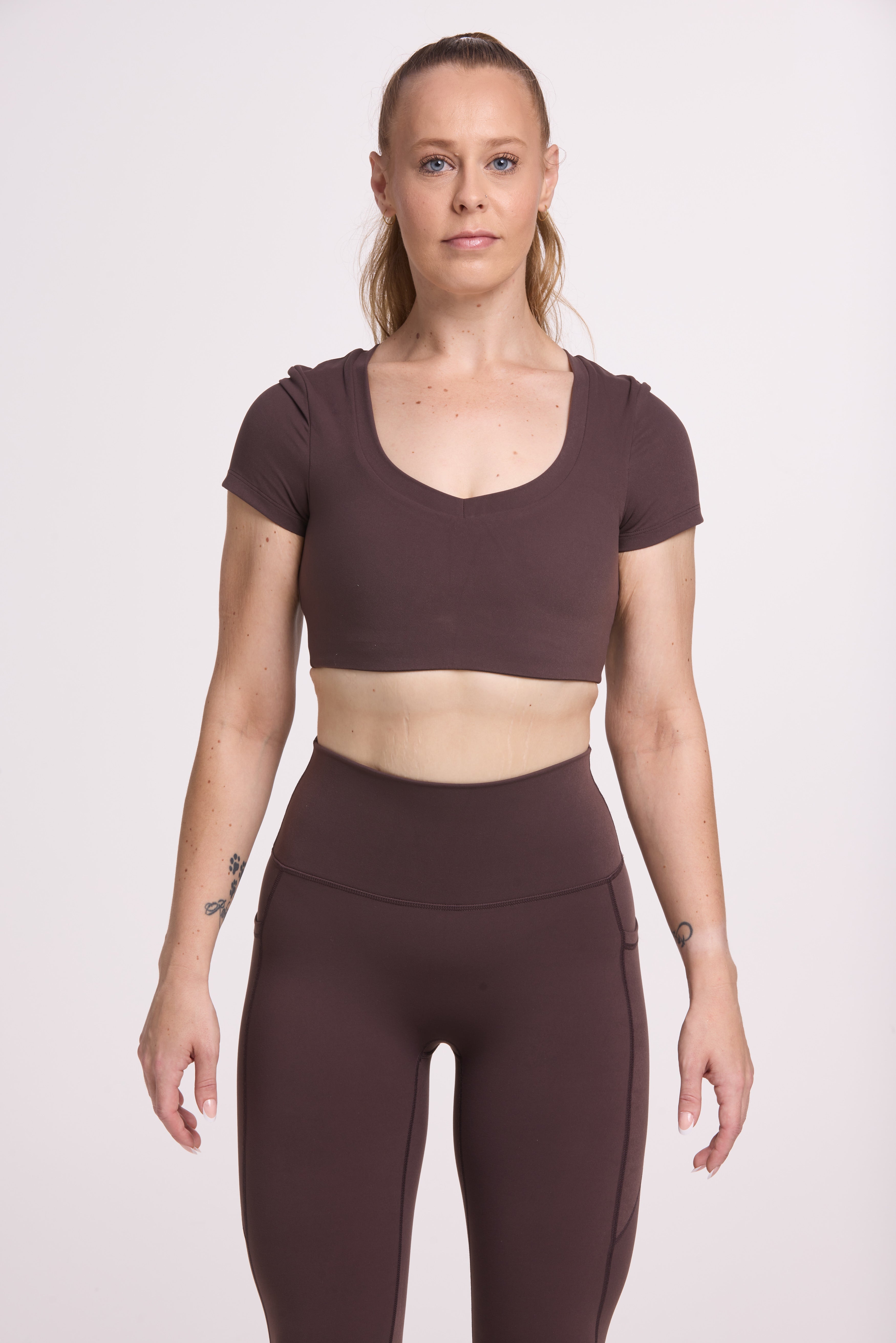 Buttery soft high waisted women's gym tights with practical pockets, sweetheart back seams for an upper glute shaping effect, and no front rise seam, paired with an V neck women's crop t-shirt with a supportive elasticated hem and triple layered fabric with removable pads for extra support in
chocolate