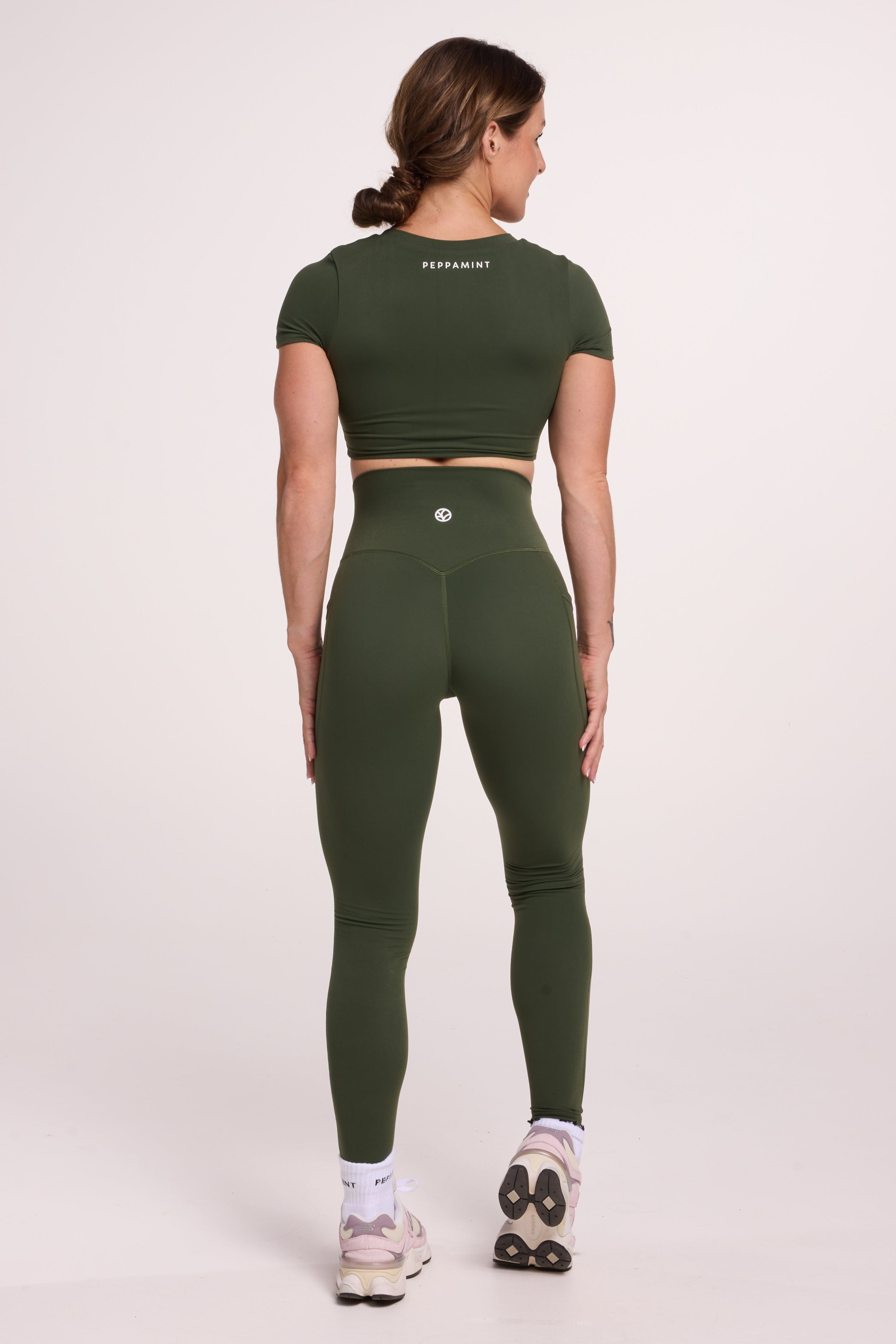 Buttery soft high waisted women's gym tights with practical pockets, sweetheart back seams for an upper glute shaping effect, and no front rise seam, paired with an V neck women's crop t-shirt with a supportive elasticated hem and triple layered fabric with removable pads for extra support in forest green