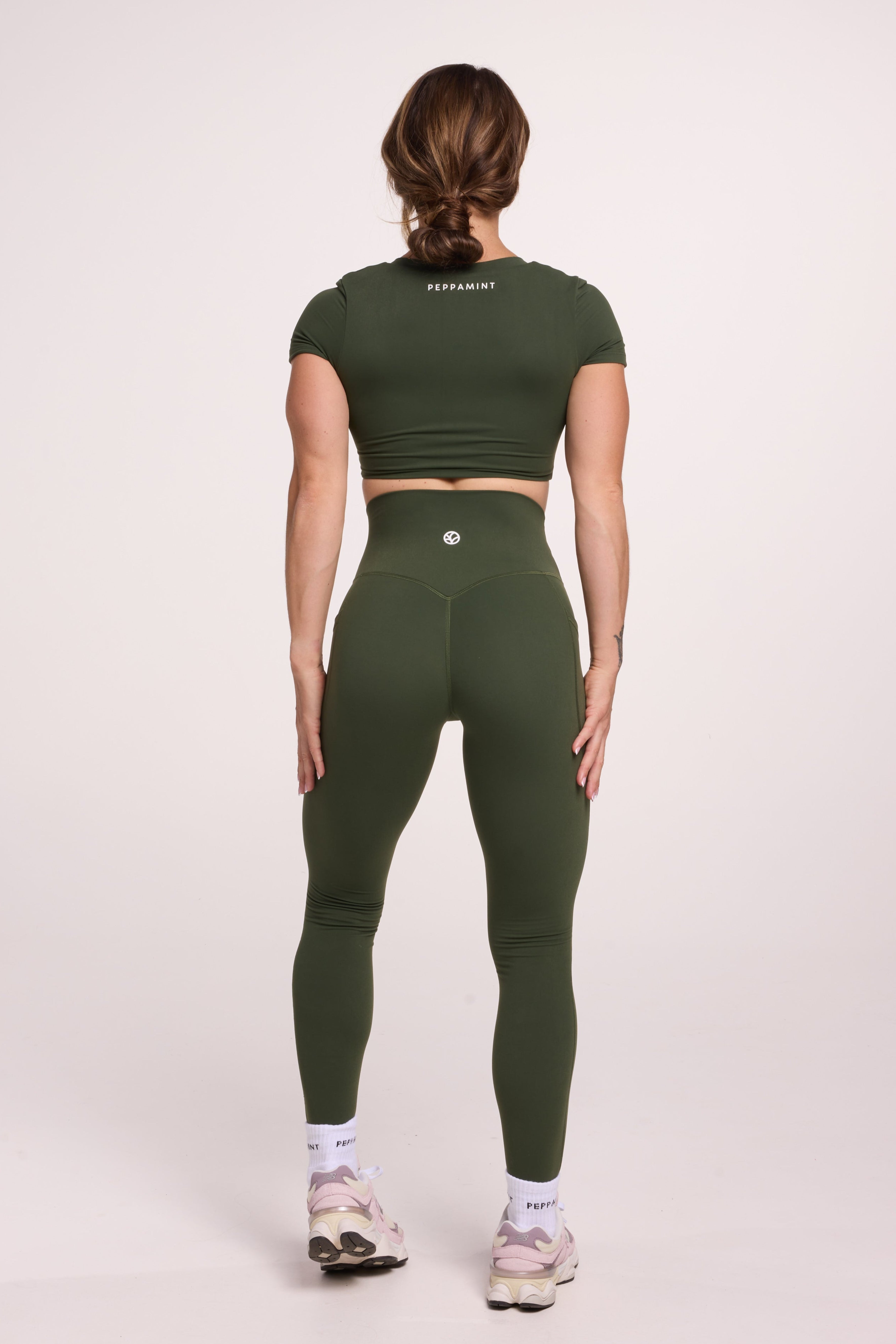 Buttery soft high waisted women's gym tights with practical pockets, sweetheart back seams for an upper glute shaping effect, and no front rise seam, paired with an V neck women's crop t-shirt with a supportive elasticated hem and triple layered fabric with removable pads for extra support in forest green
