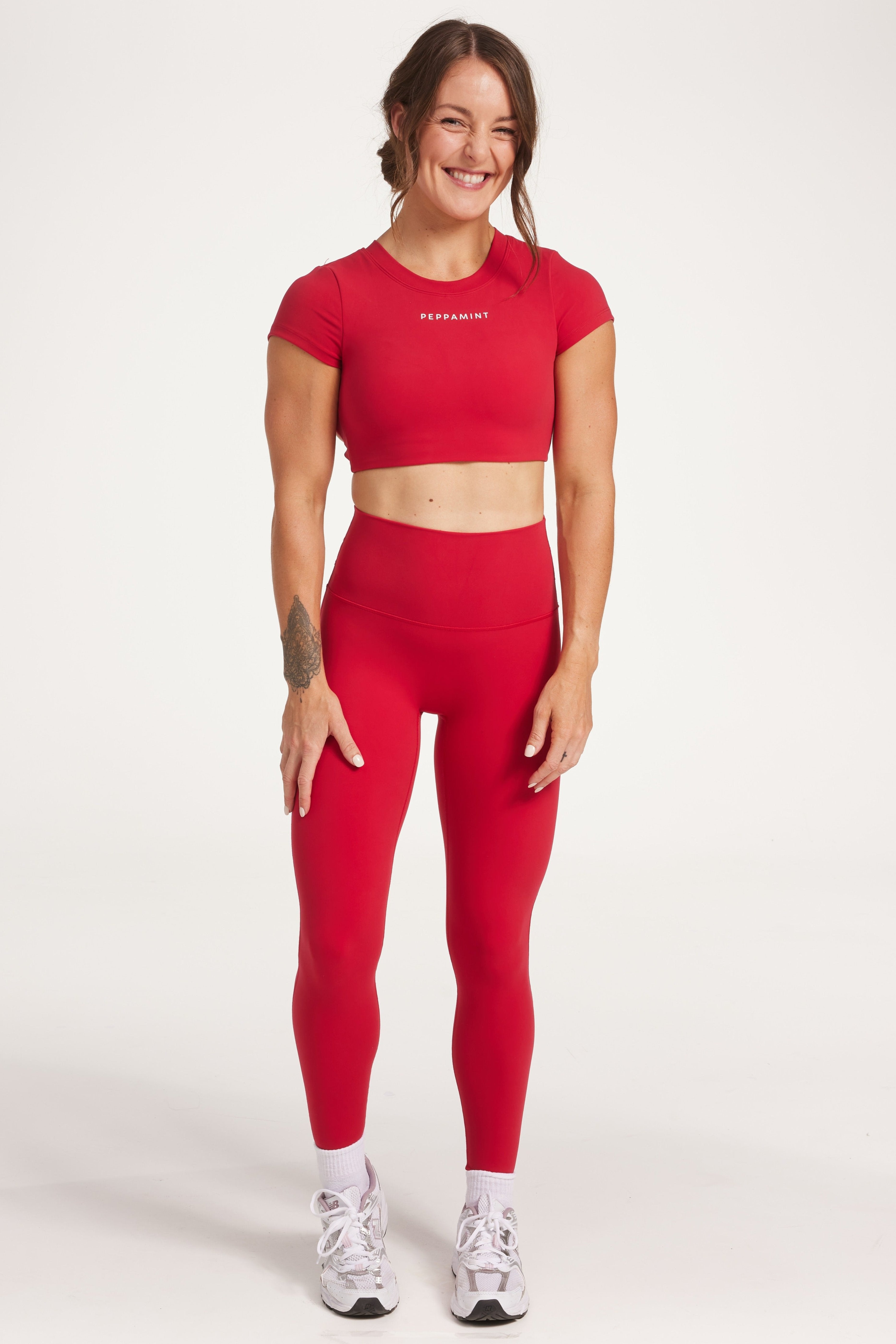 Buttery soft high waisted women's gym tights with curved hem stitched detailing for a butt shaping effect, and no front rise seam, paired with an open back women's crop t-shirt with a supportive elasticated hem and triple layered fabric with removable pads for extra support and aesthetic cross back straps in Raspberry red.