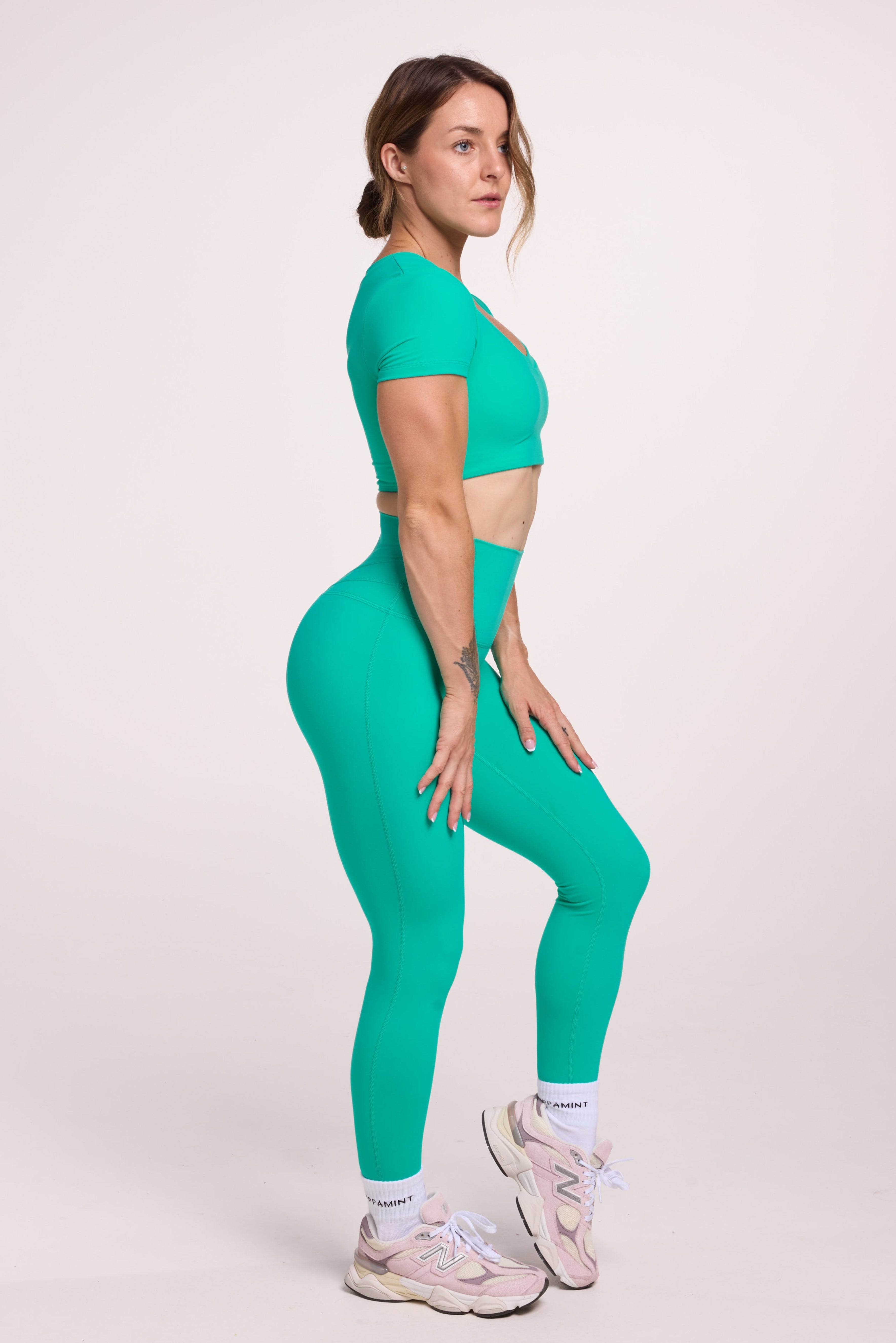Buttery soft high waisted women's gym tights with curved back seam stitched detailing for a butt shaping effect, and no front rise seam paired with an V neck women's crop t-shirt with a supportive elasticated hem and triple layered fabric with removable pads for extra support in
cyan green