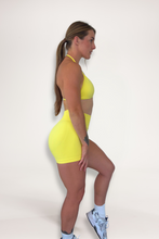 Load image into Gallery viewer, Seamless shorts with booty contouring panels, glute shaping seams, a thick supportive waistband paired with a minimalistic bra with sleek back straps and halter neck design for showcasing the back gains in buttercup yellow