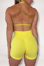 Load image into Gallery viewer, Seamless shorts with booty contouring panels, glute shaping seams, a thick supportive waistband paired with a minimalistic bra with sleek back straps and halter neck design for showcasing the back gains in buttercup yellow