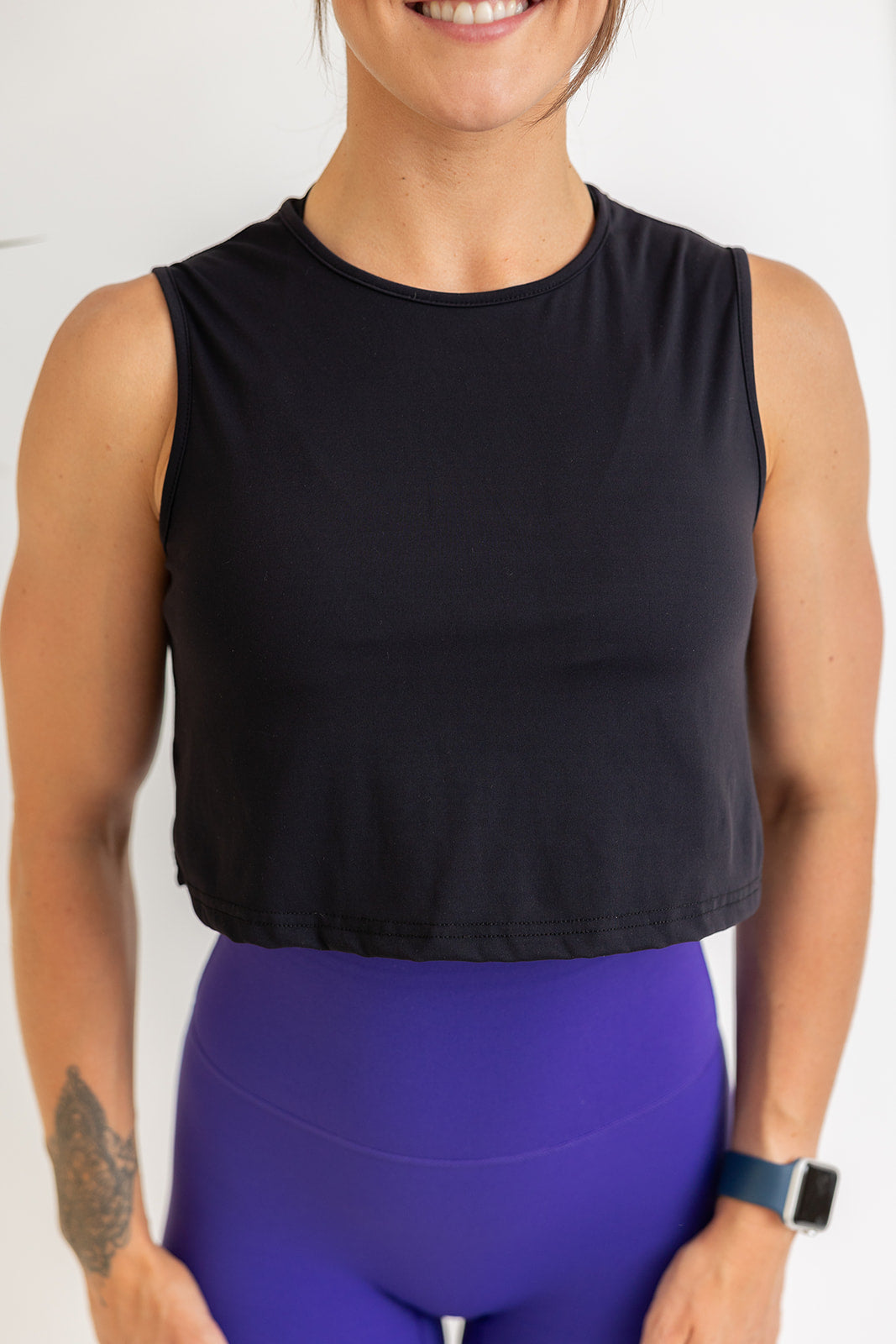 buttery soft crop length tank top in black with subtle stitched logo tag