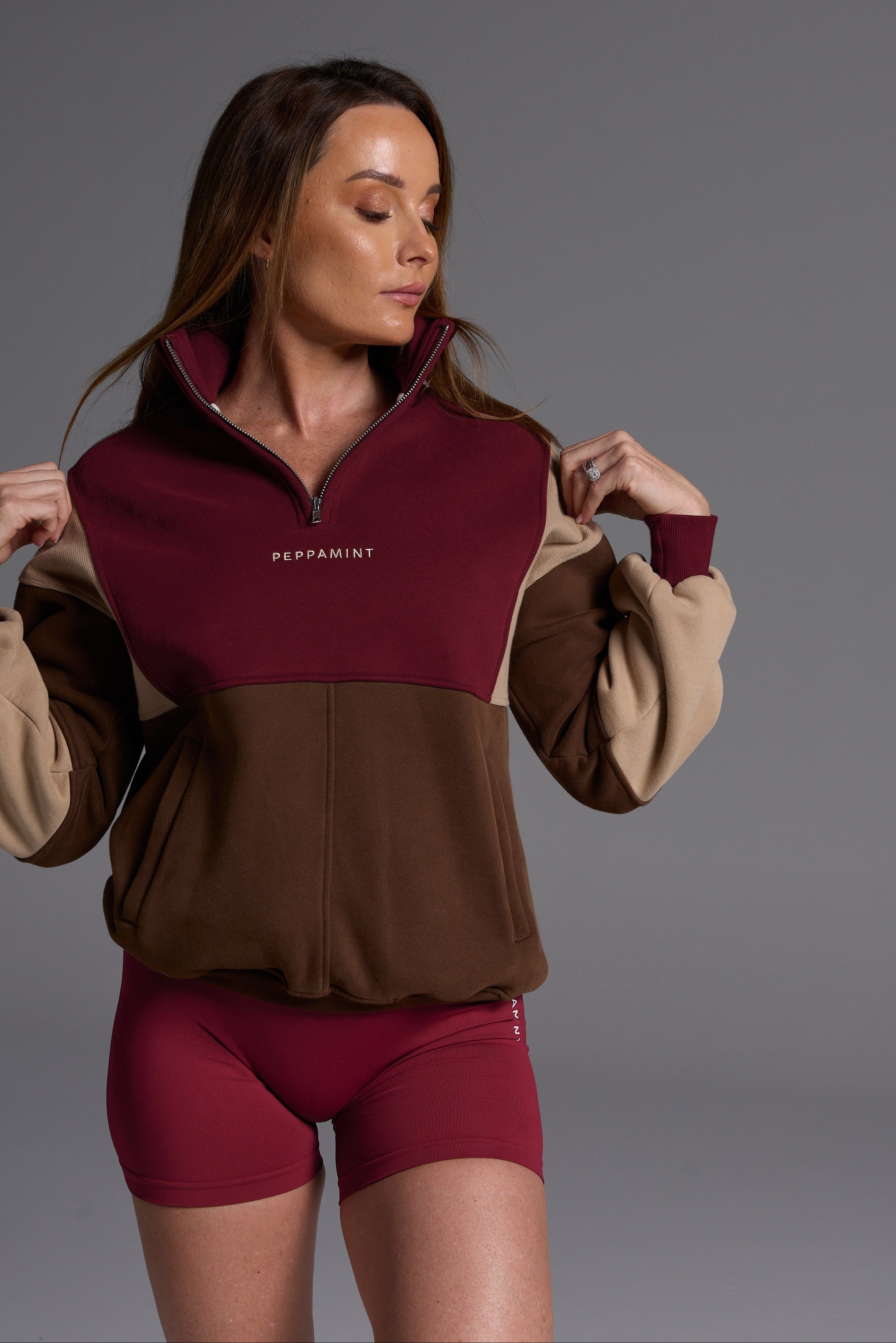 1/4 zip fleece jumper with double collar, ribbed stretchy fabric panel inserts, and two convenient zip pockets in a wine, chocolate and beige colour block design.
