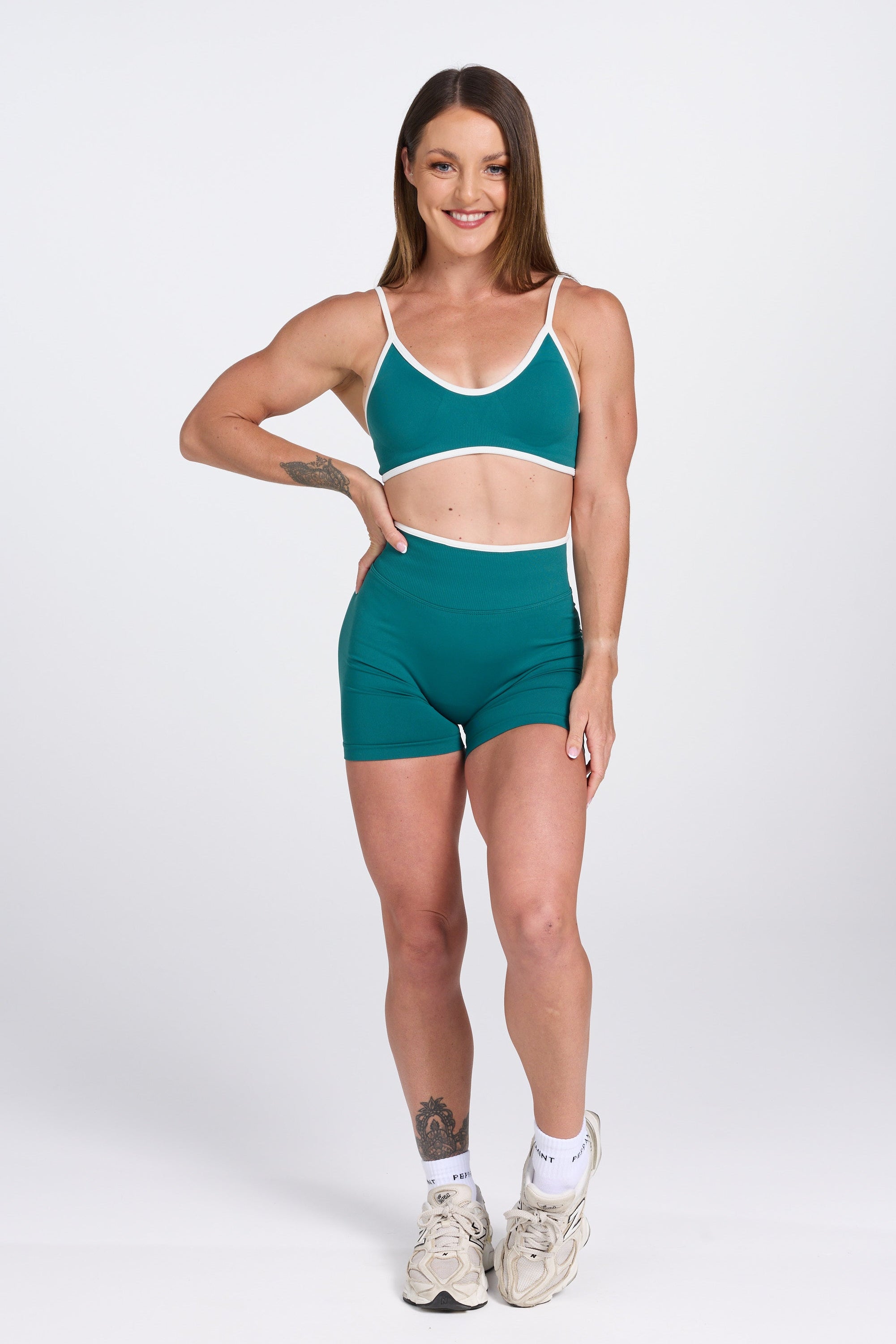 Seamless gym bra, with luxe white trim and adjustable back straps in teal colour.