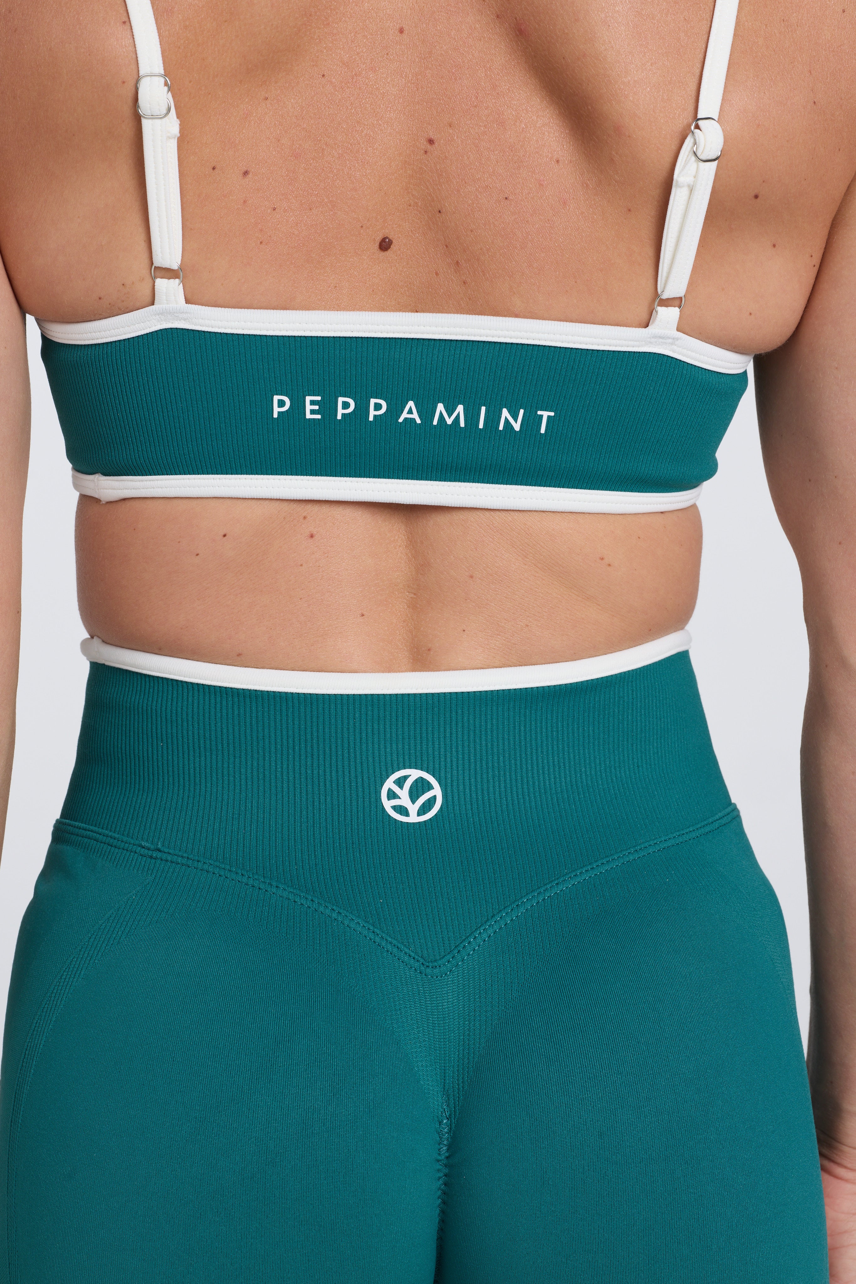 Seamless gym bra, with luxe white trim and adjustable back straps in teal colour.