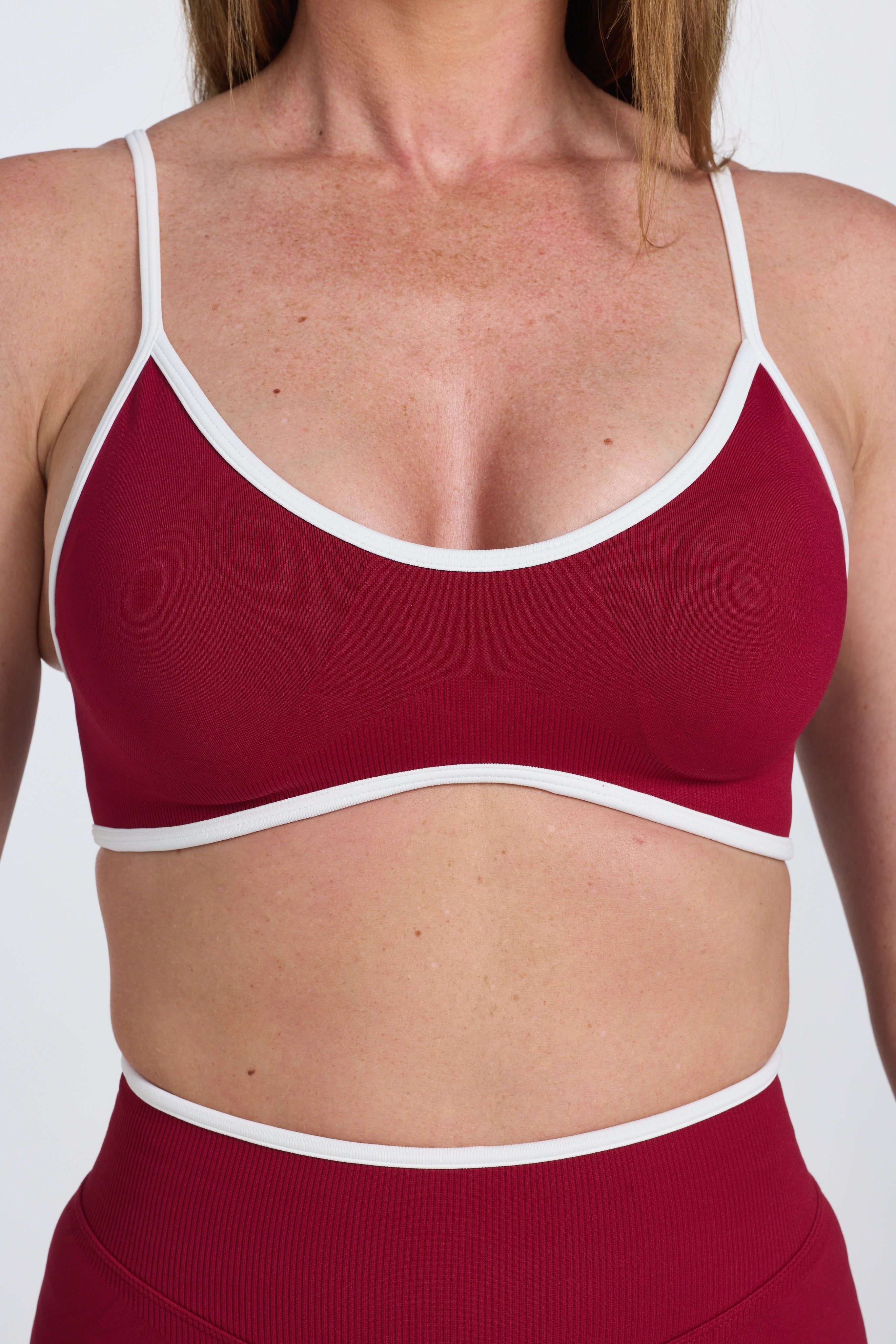 Seamless gym bra, with luxe white trim and adjustable back straps in wine colour.