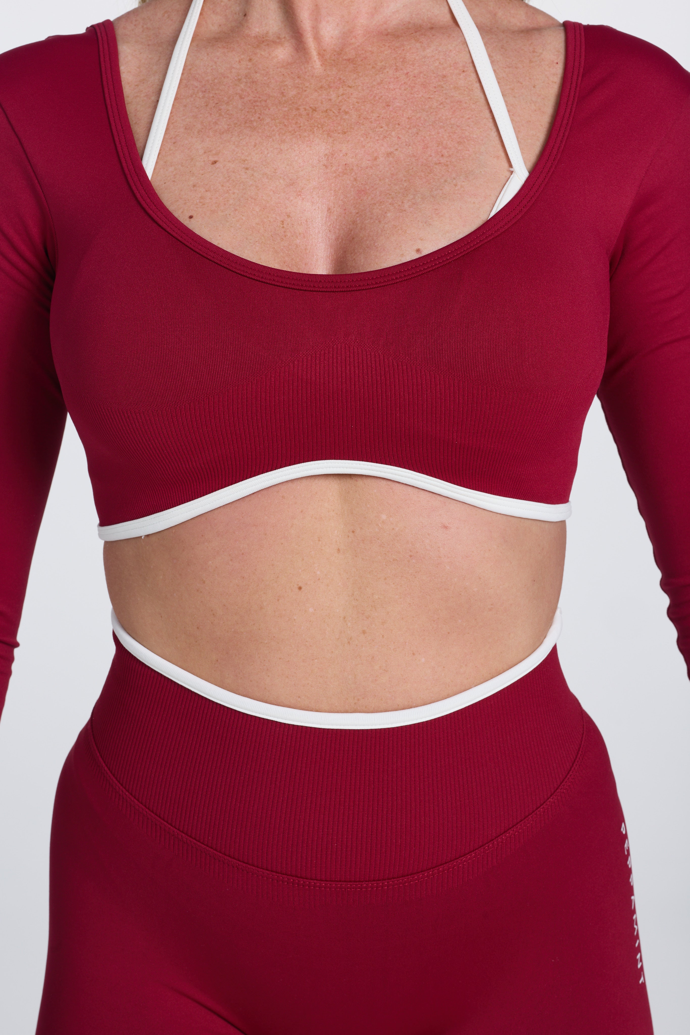 Long sleeve seamless crop top, with built in white contrasting bra, luxe white trim, and adjustable halter strap in wine colour.