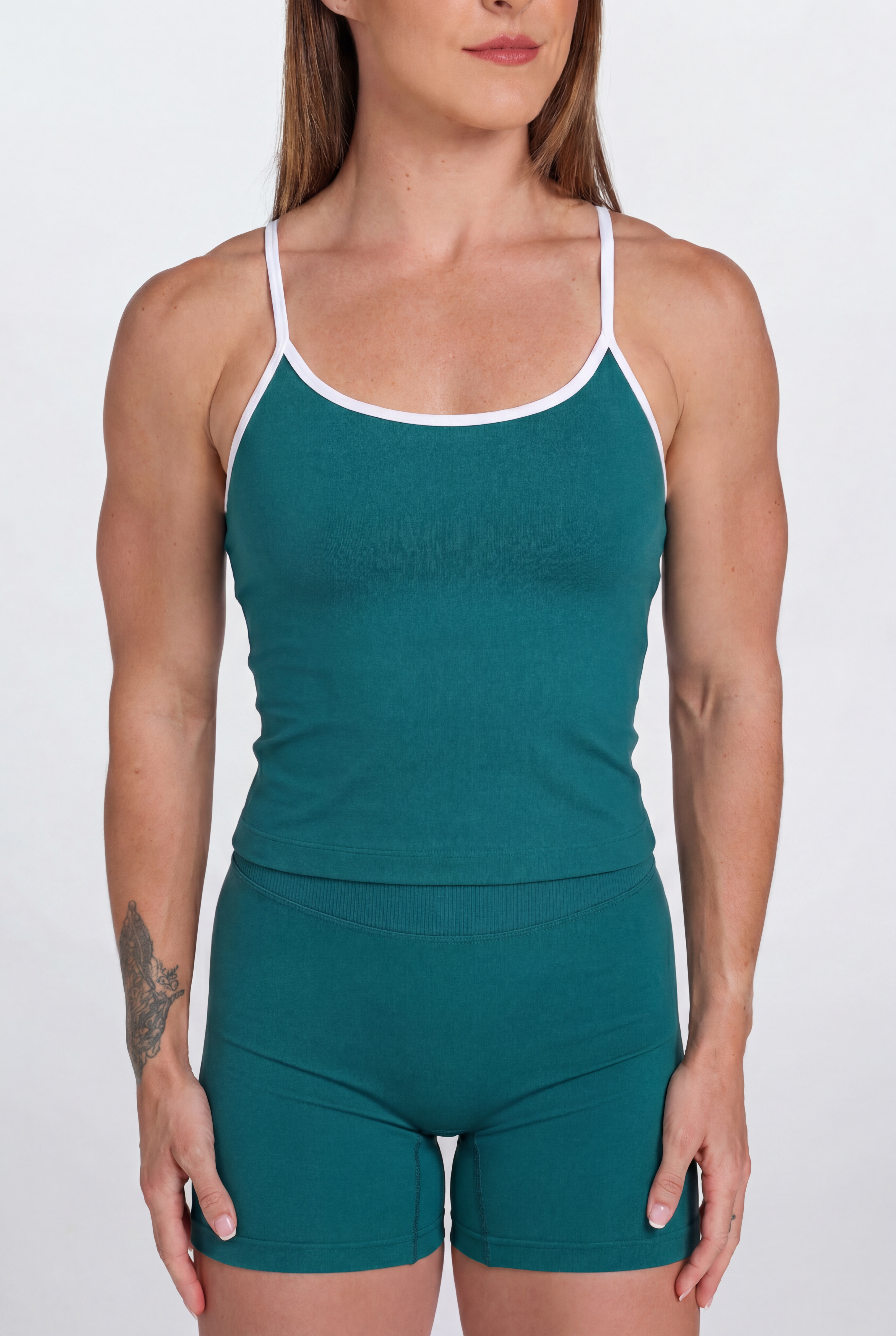 Woman wearing a Teal tank top and shorts set with white trim on a white background