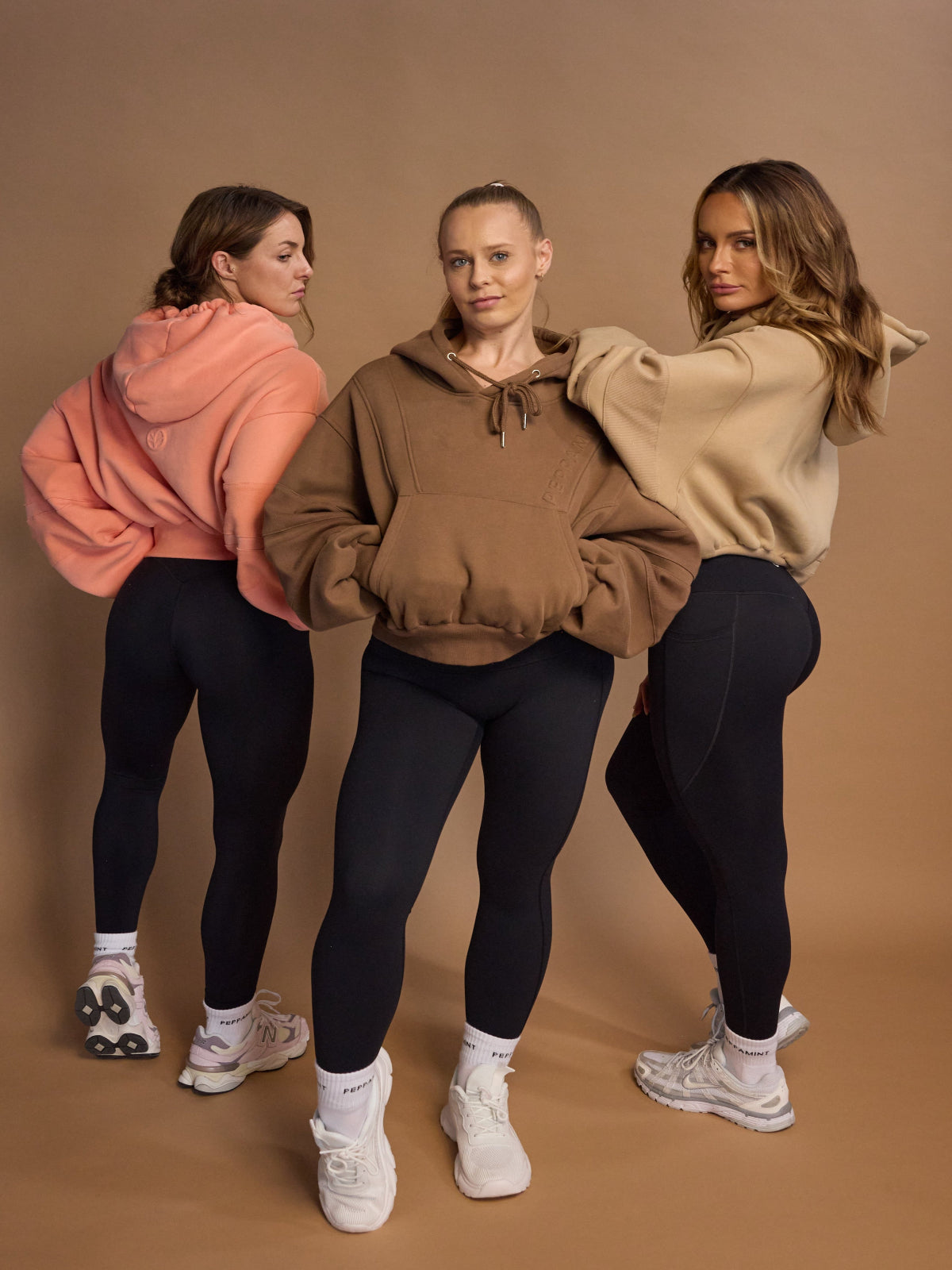 Oversize batwing hoodie, hip length, with slouchy oversized sleeves, piped seams, iconic ribbed panels and a kangaroo pocket with a hidden phone pocket inside in chocolate brown, coral and a beige sand colour