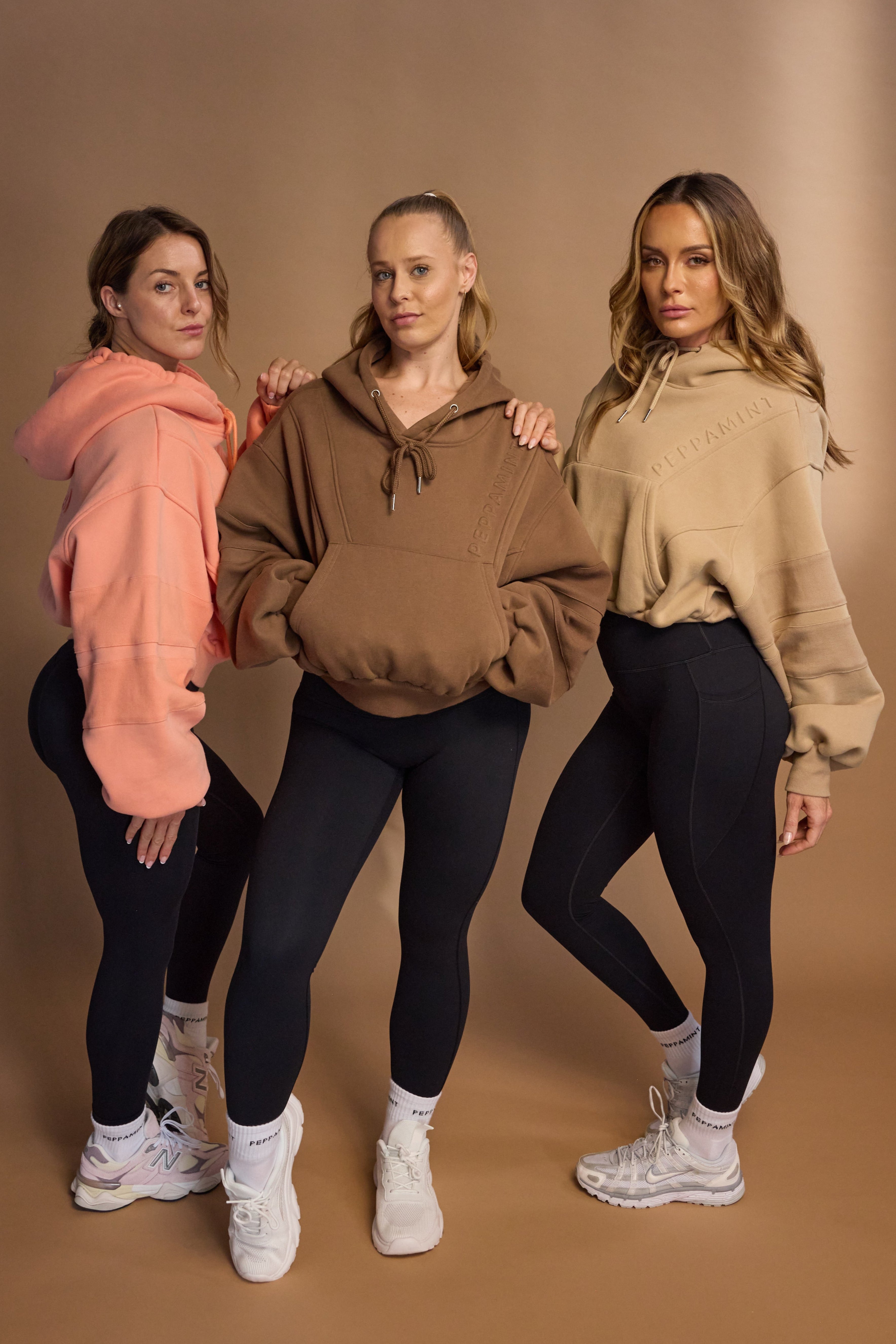 Oversize batwing hoodie, hip length, with slouchy oversized sleeves, piped seams, iconic ribbed panels and a kangaroo pocket with a hidden phone pocket inside in chocolate brown, coral and a beige sand colour