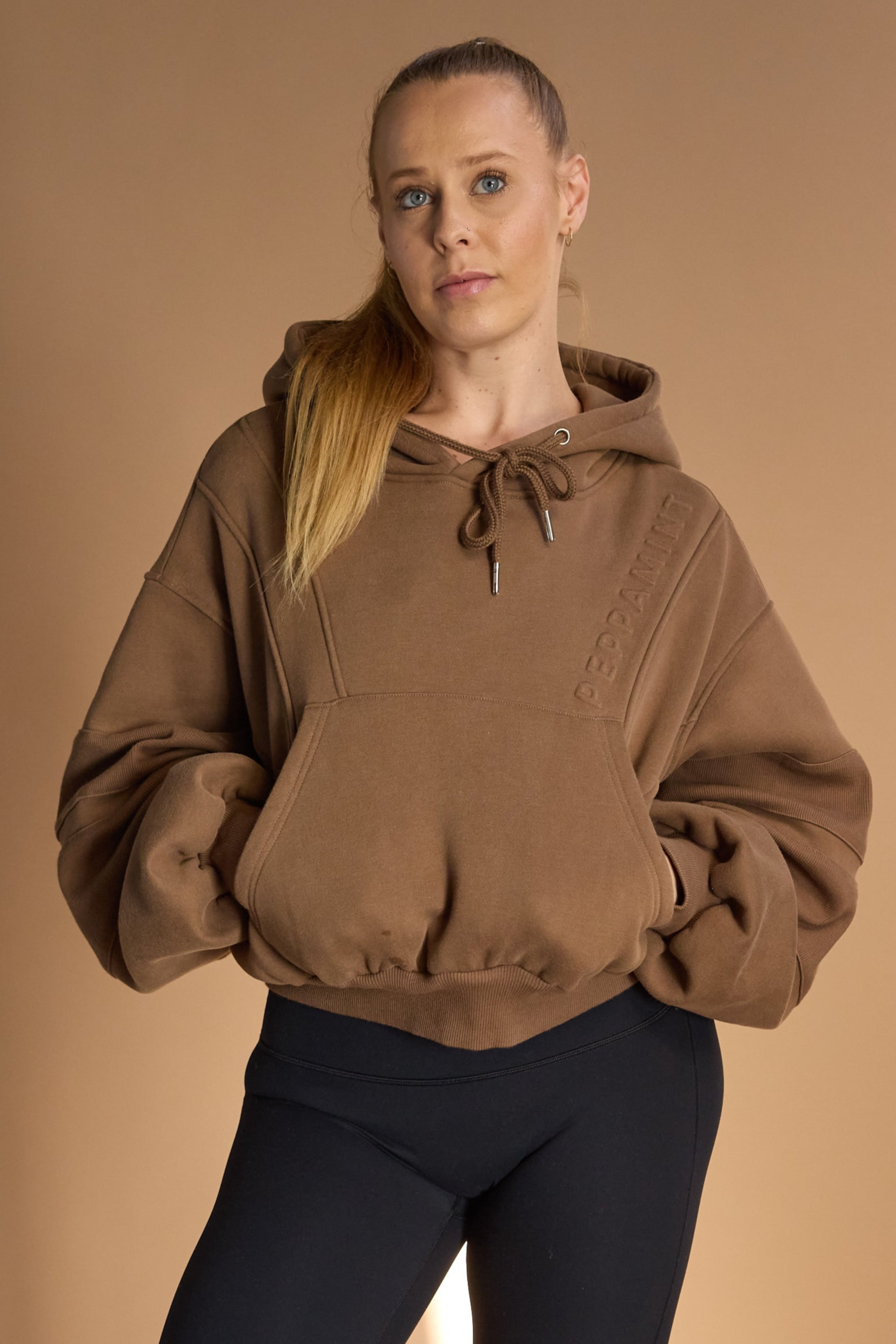Oversize batwing hoodie, hip length, with slouchy oversized sleeves, piped seams, iconic ribbed panels and a kangaroo pocket with a hidden phone pocket inside in chocolate brown colour