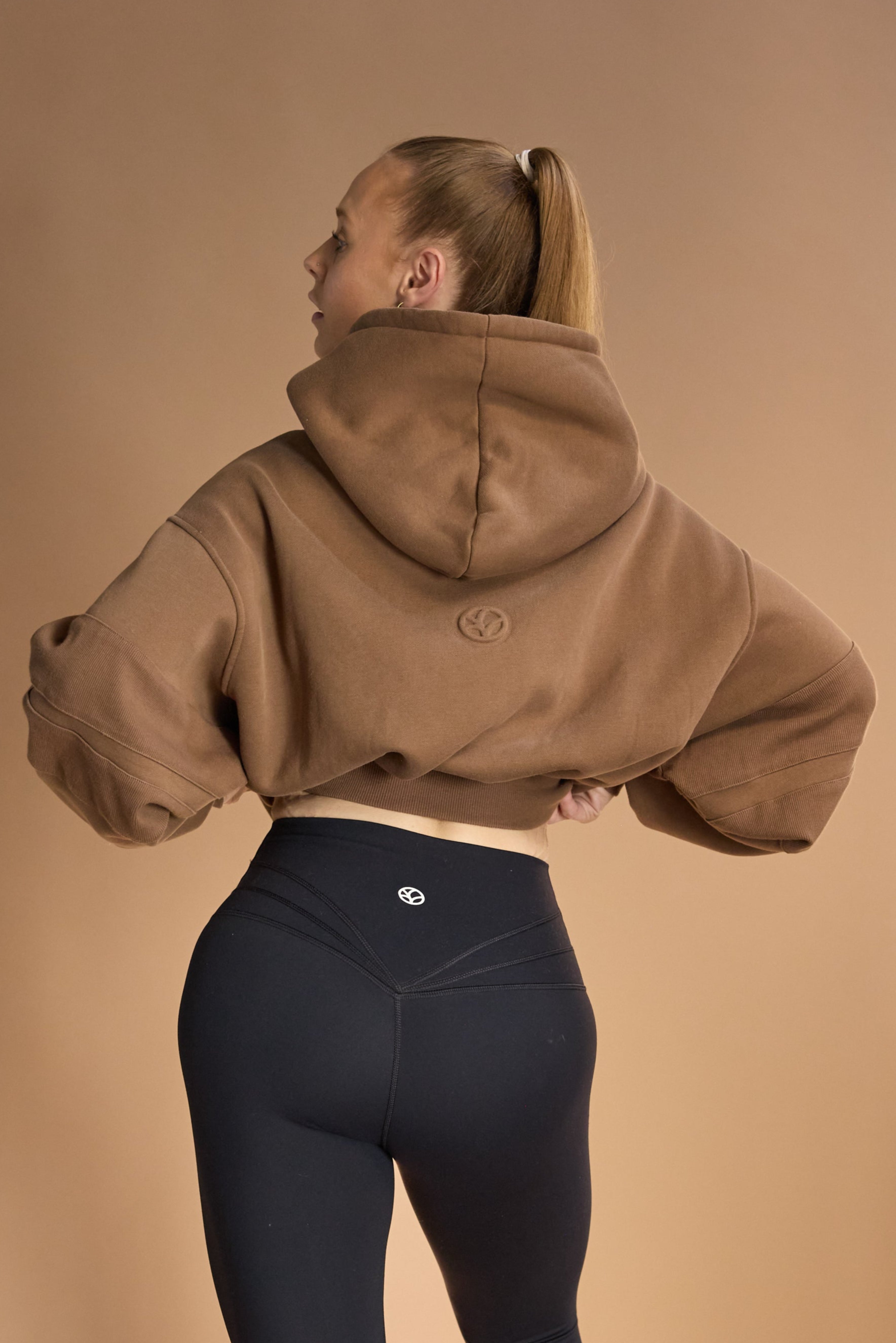 Oversize batwing hoodie, hip length, with slouchy oversized sleeves, piped seams, iconic ribbed panels and a kangaroo pocket with a hidden phone pocket inside in chocolate brown colour