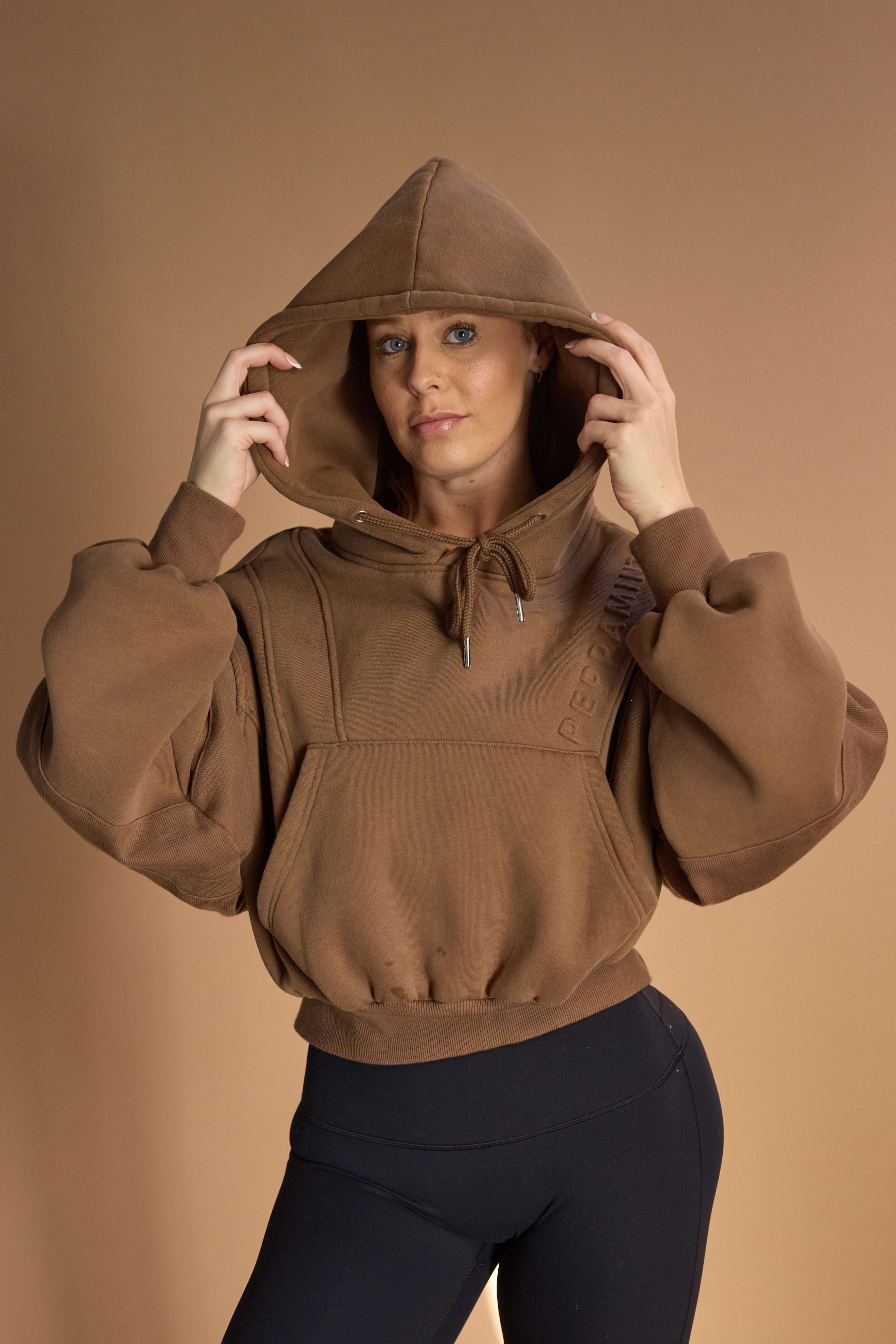 Oversize batwing hoodie, hip length, with slouchy oversized sleeves, piped seams, iconic ribbed panels and a kangaroo pocket with a hidden phone pocket inside in chocolate brown colour