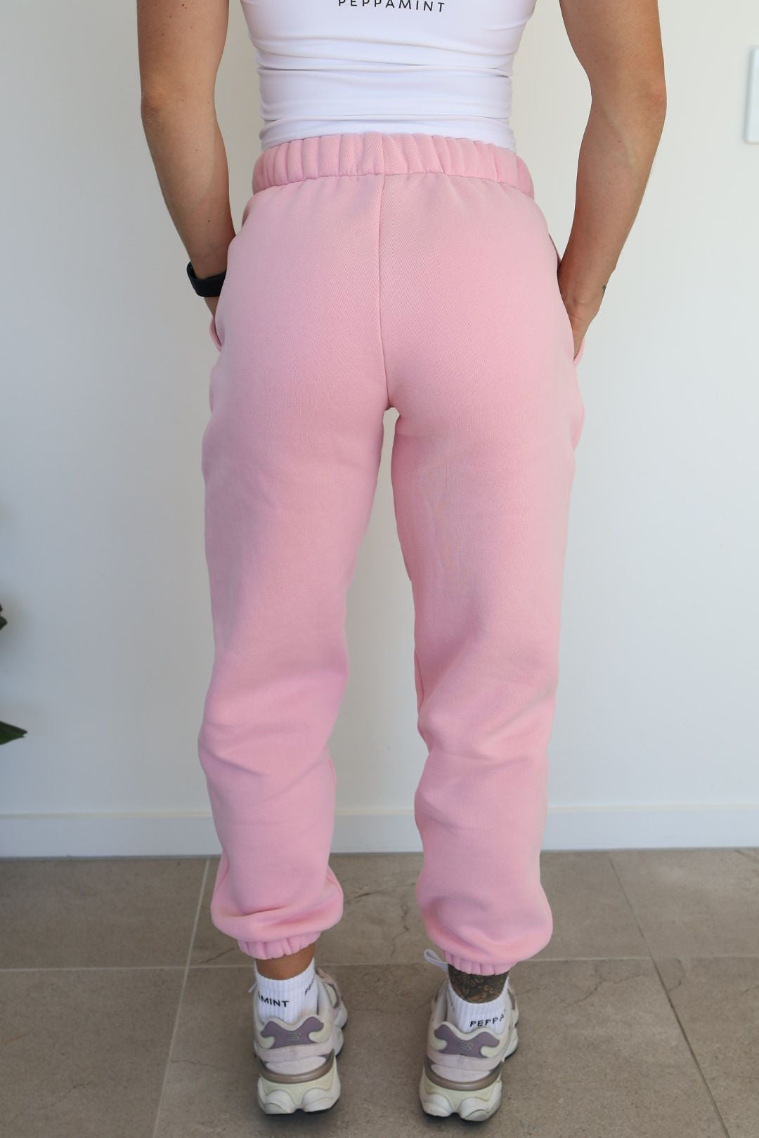 Fleece lined joggers in baby pink with elasticated waistband, drawstring, two side pockets and a subtle embossed logo icon on left pocket