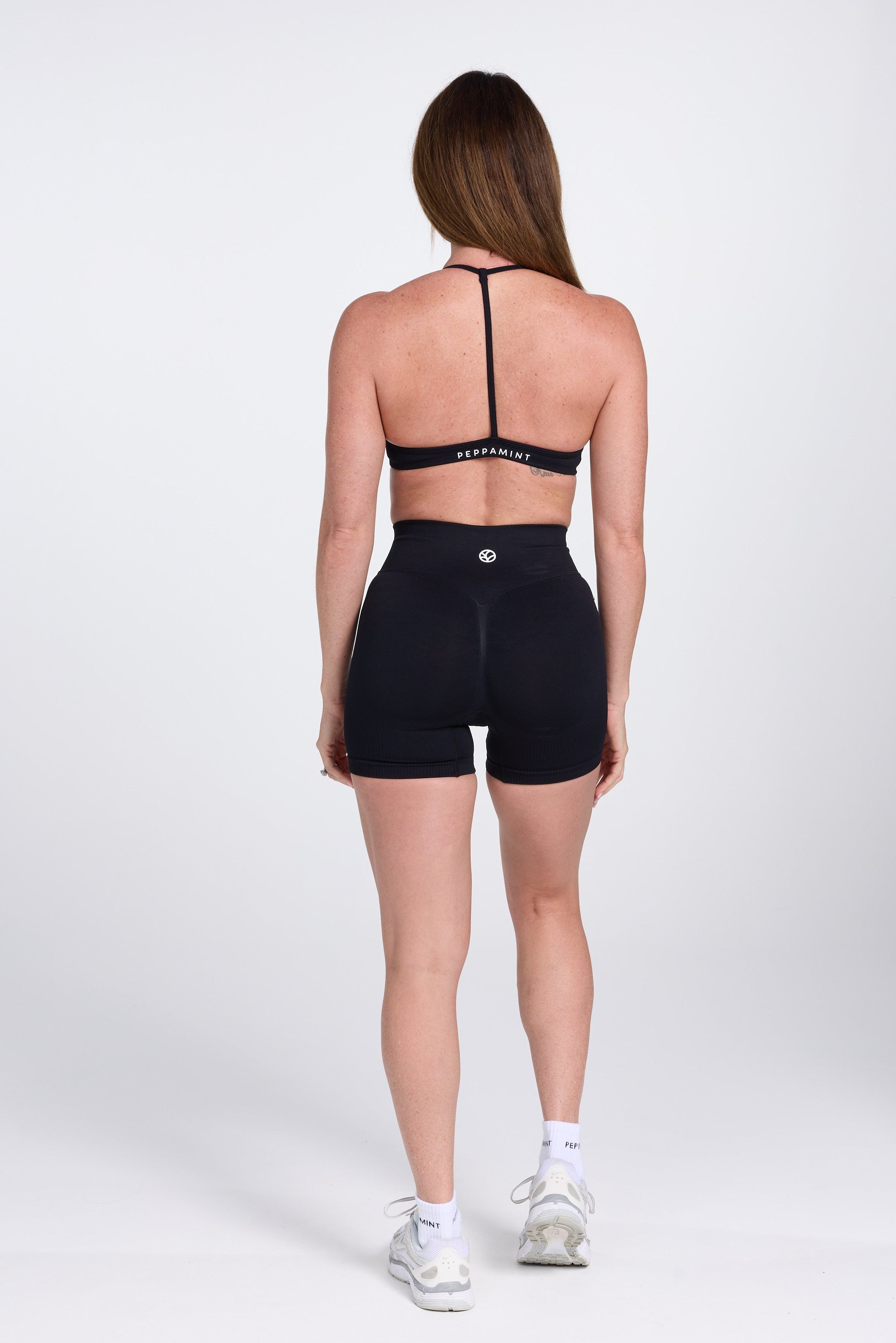 Seamless women’s gym bra with an ultra thin racerback strap design, with white PEPPAMINT branding on the back strap paired with high waisted gym shorts with booty contouring panels, invisible scrunch technology, sweetheart shaped back seams and thick supportive fabric iblack