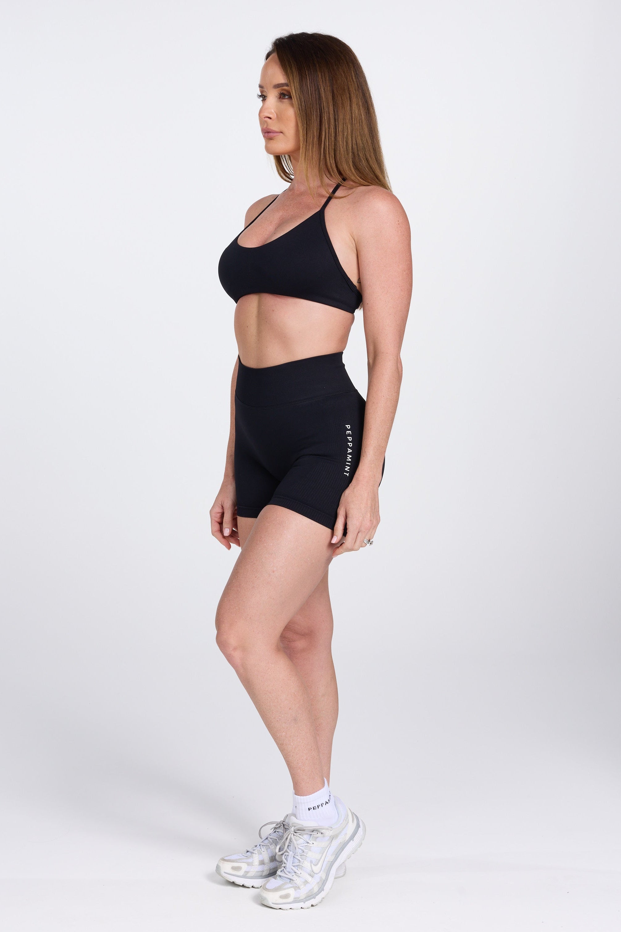 Seamless women’s gym bra with an ultra thin racerback strap design, with white PEPPAMINT branding on the back strap paired with high waisted gym shorts with booty contouring panels, invisible scrunch technology, sweetheart shaped back seams and thick supportive fabric iblack