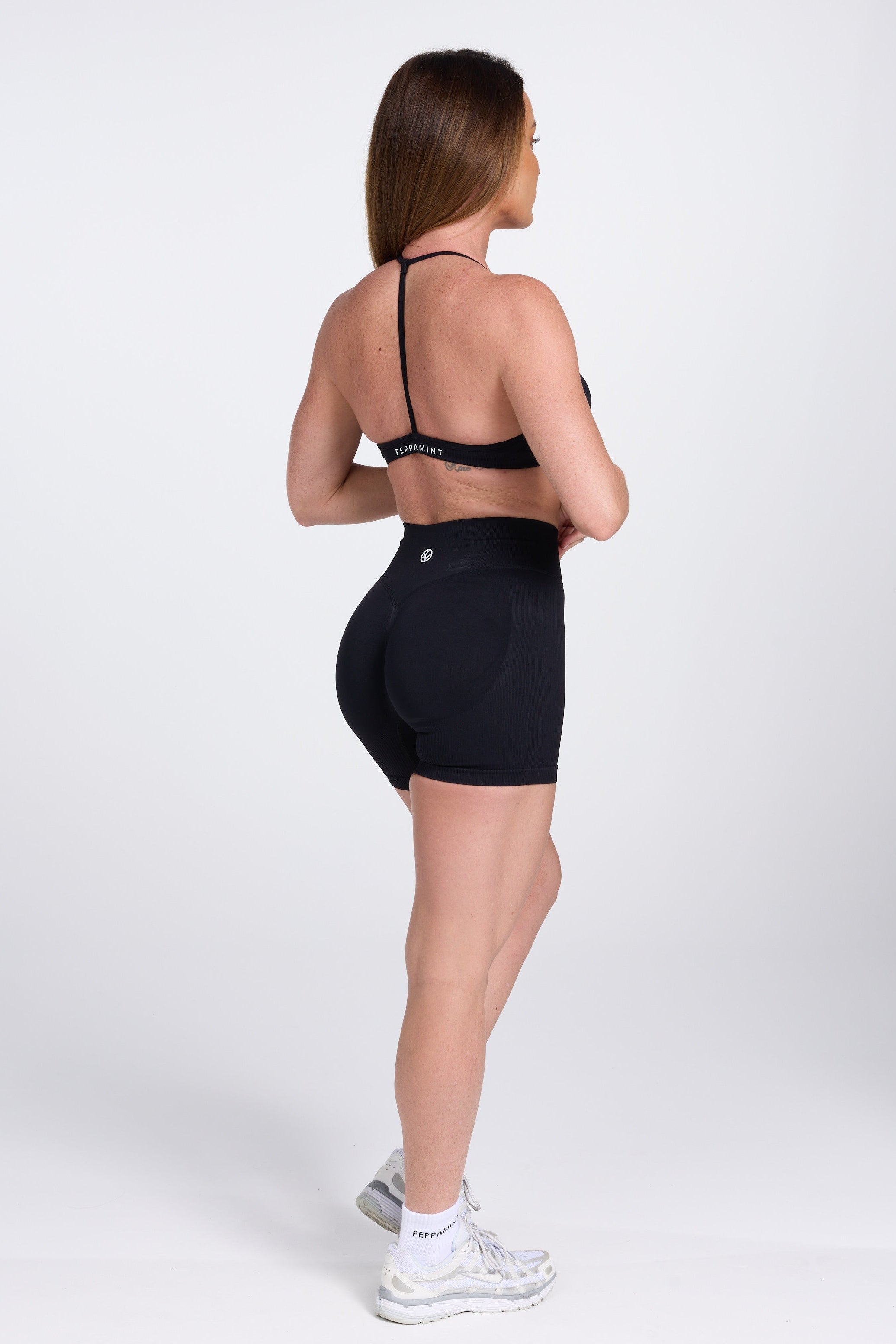 Seamless women’s gym bra with an ultra thin racerback strap design, with white PEPPAMINT branding on the back strap paired with high waisted gym shorts with booty contouring panels, invisible scrunch technology, sweetheart shaped back seams and thick supportive fabric iblack