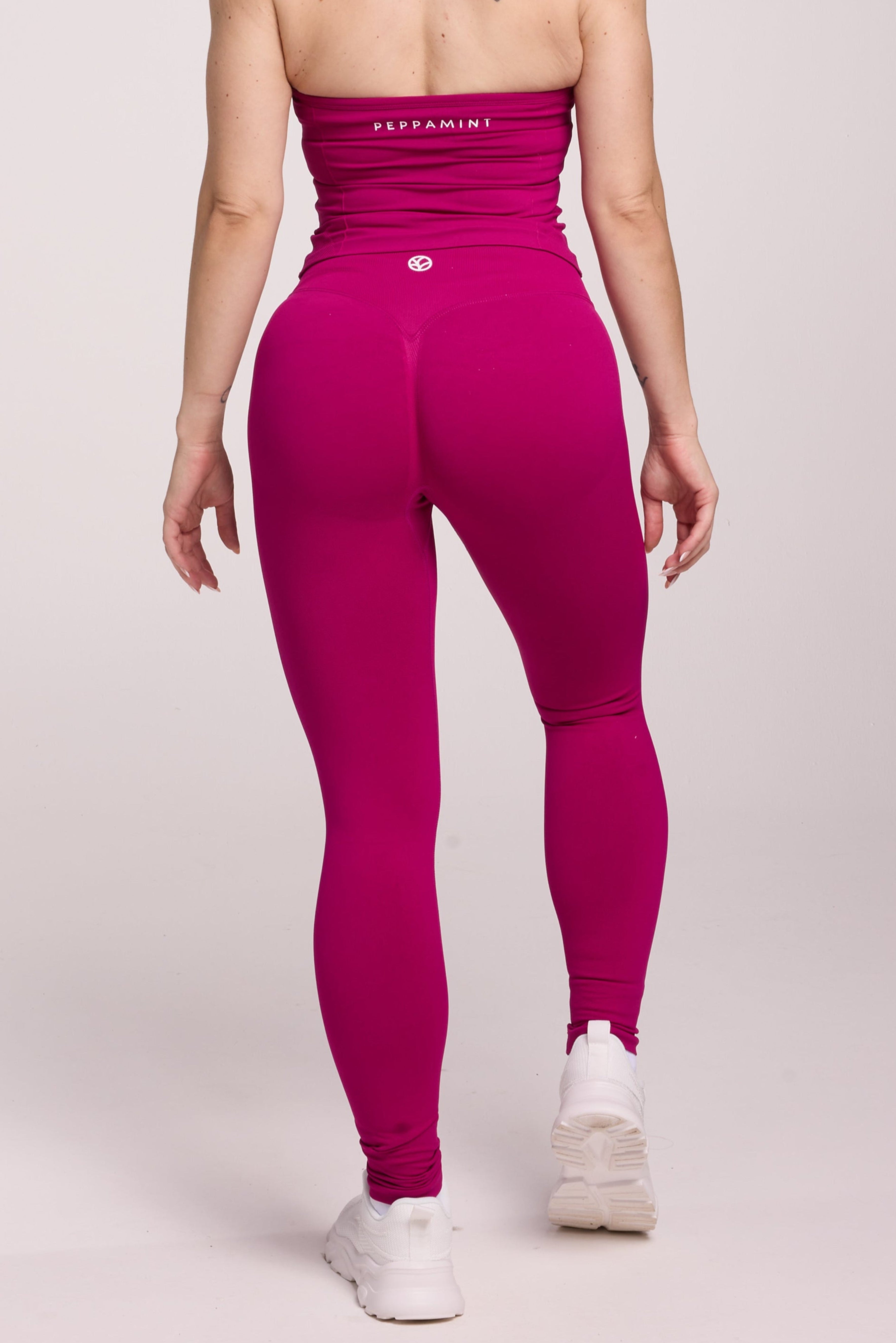 Halter neck tank top with breast contouring panels and a ruched front seam, a built in bra, and an open upper back design and seamless gym tights with booty contouring panels, invisible scrunch technology, sweetheart shaped back seams and thick supportive fabrics in magenta colour