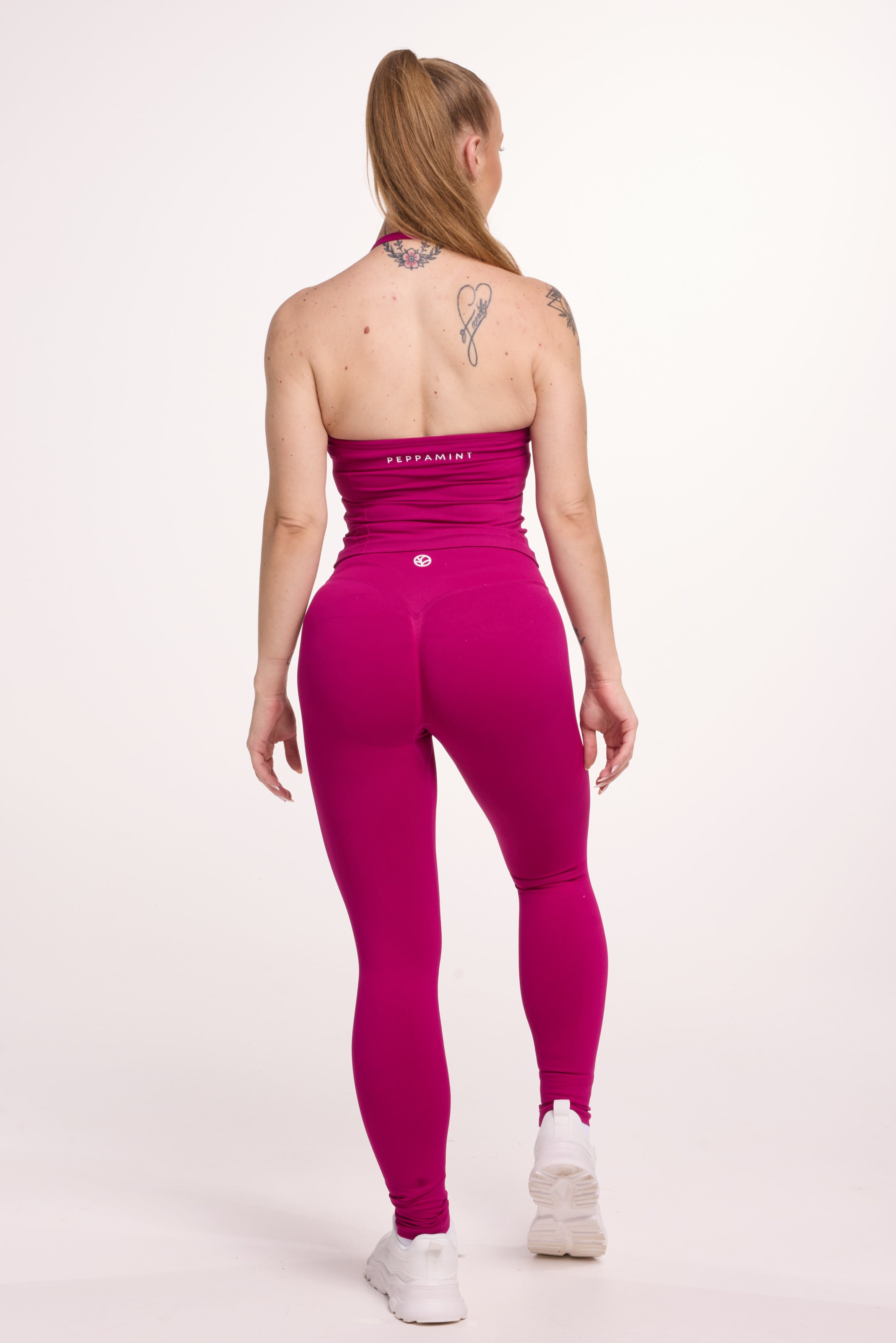 Halter neck tank top with breast contouring panels and a ruched front seam, a built in bra, and an open upper back design and seamless gym tights with booty contouring panels, invisible scrunch technology, sweetheart shaped back seams and thick supportive fabrics in magenta