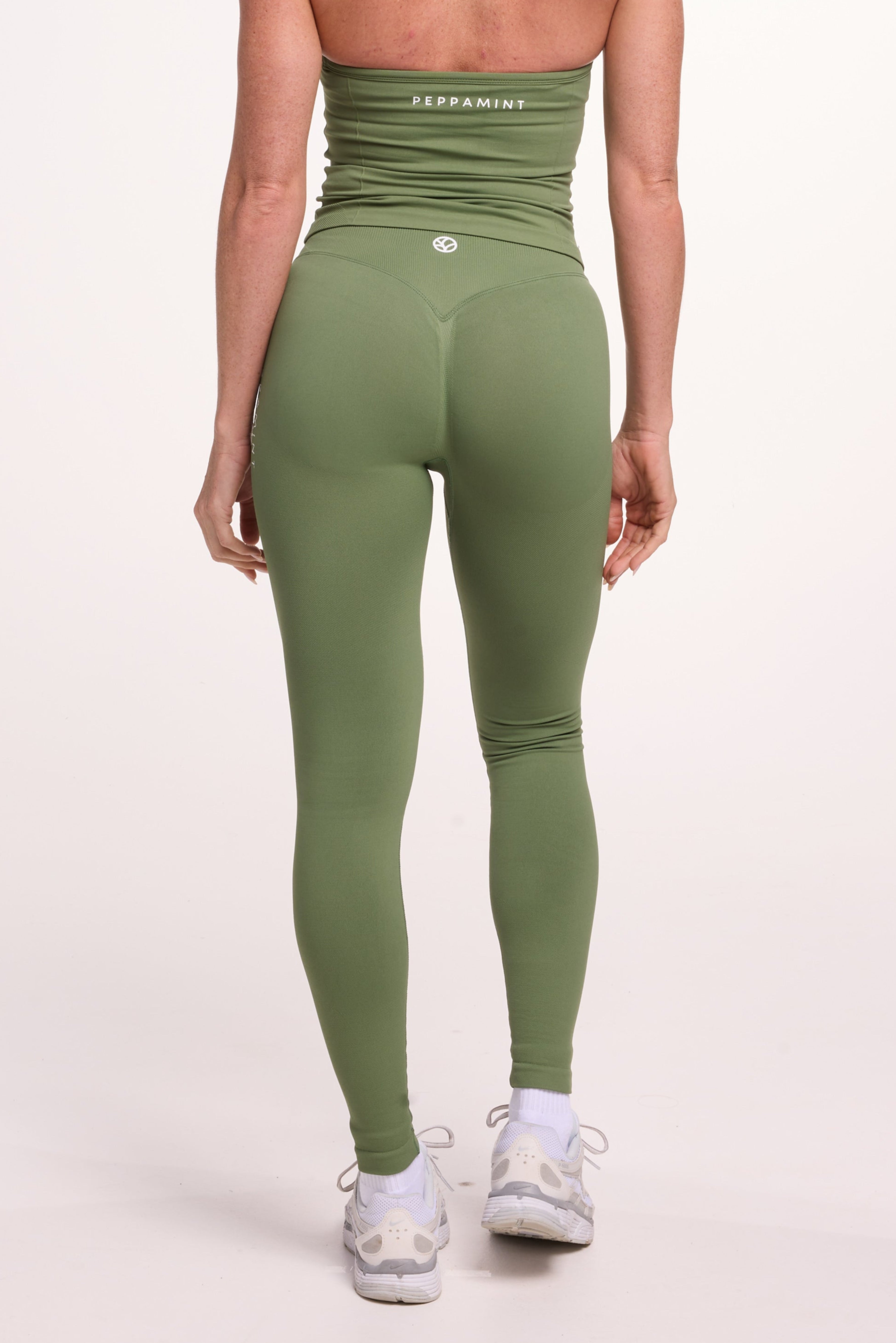 Halter neck tank top with breast contouring panels and a ruched front seam, a built in bra, and an open upper back design and seamless gym tights with booty contouring panels, invisible scrunch technology, sweetheart shaped back seams and thick supportive fabrics in mermaid green colour