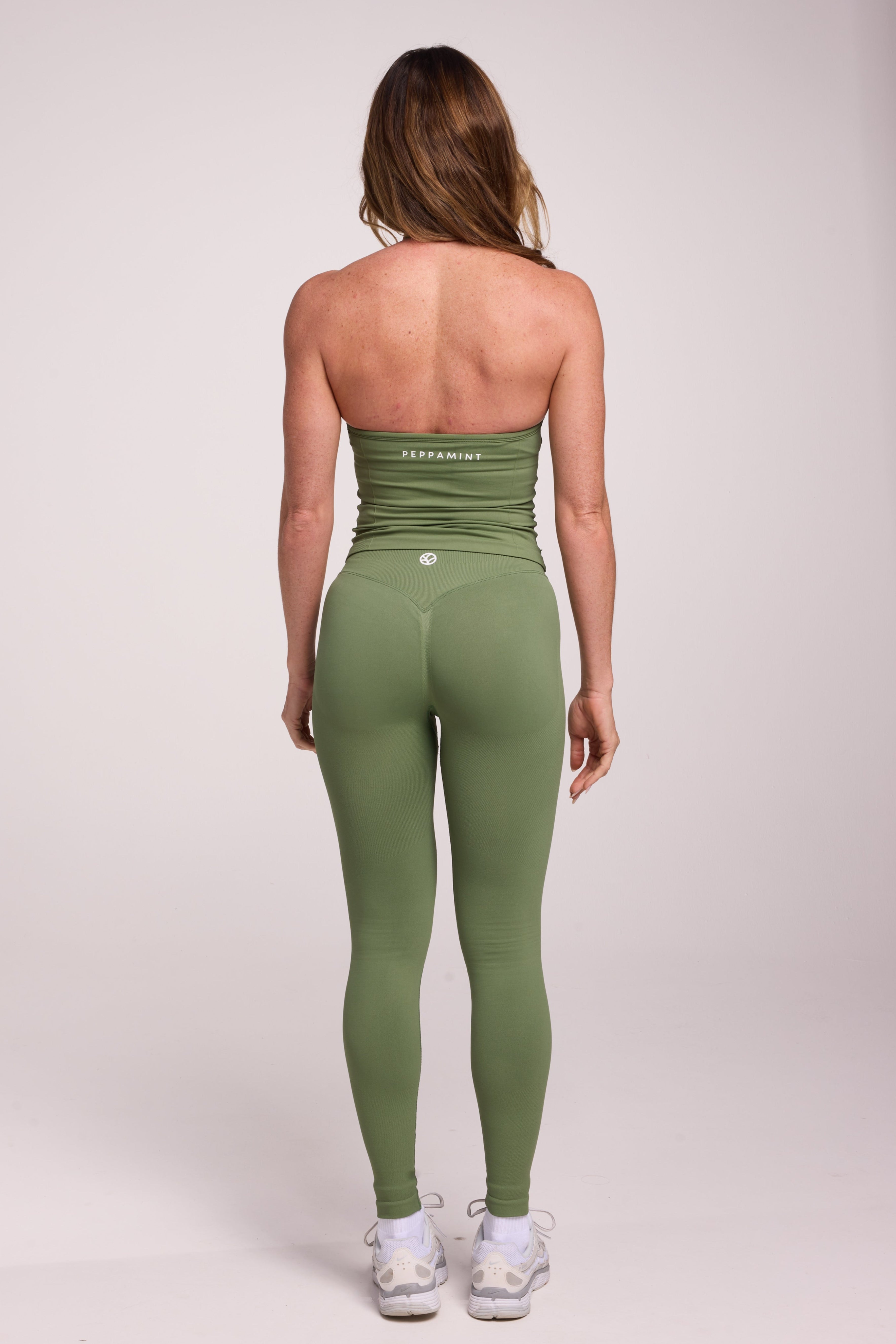 Halter neck tank top with breast contouring panels and a ruched front seam, a built in bra, and an open upper back design and seamless gym tights with booty contouring panels, invisible scrunch technology, sweetheart shaped back seams and thick supportive fabrics in mermaid green colour