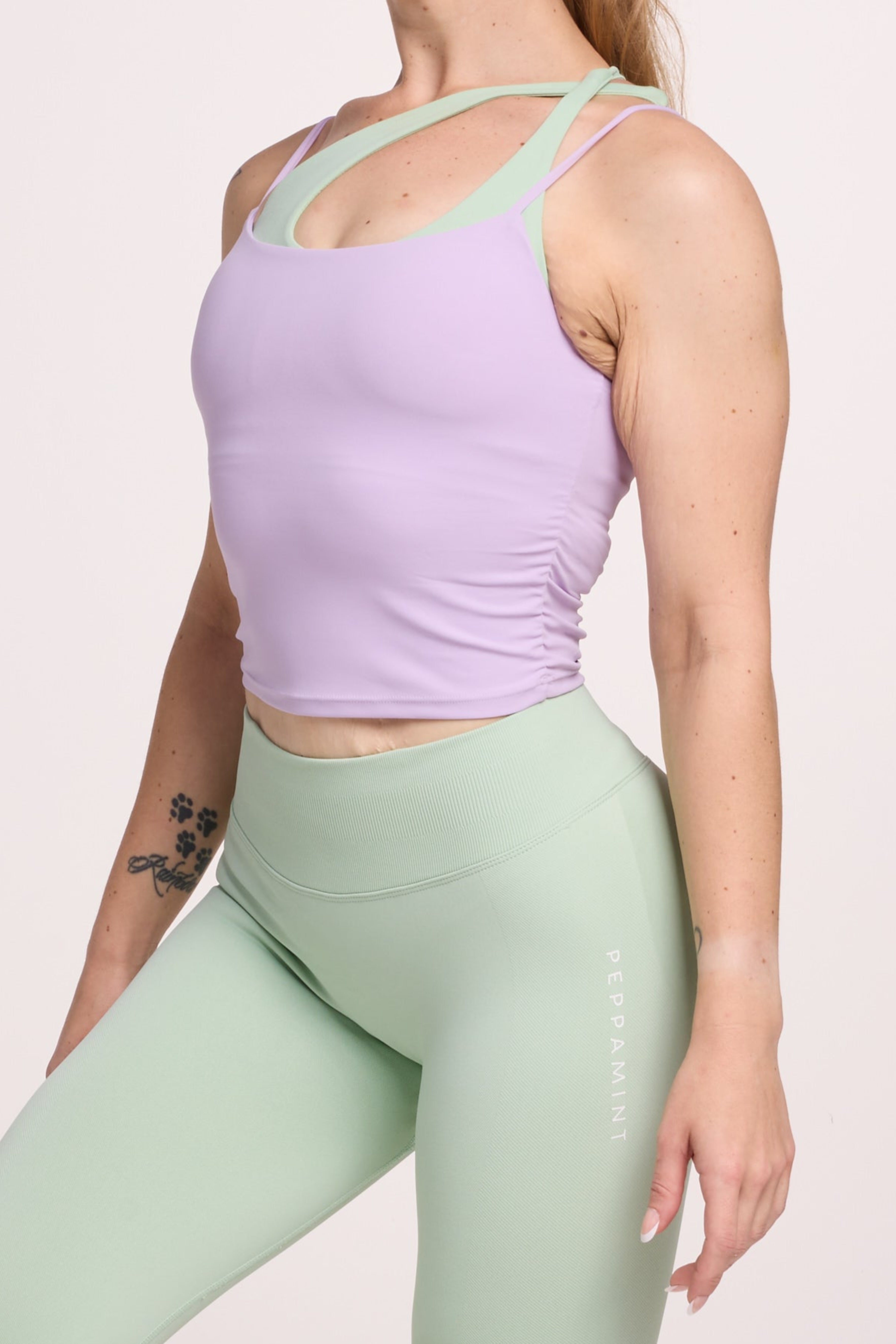 Buttery soft singlet with ruched side seams, spaghetti straps and built in shelf bra with removable pads in lavender with seamless gym tights with booty contouring panels, invisible scrunch technology, sweetheart shaped back seams and thick supportive fabric in mist green