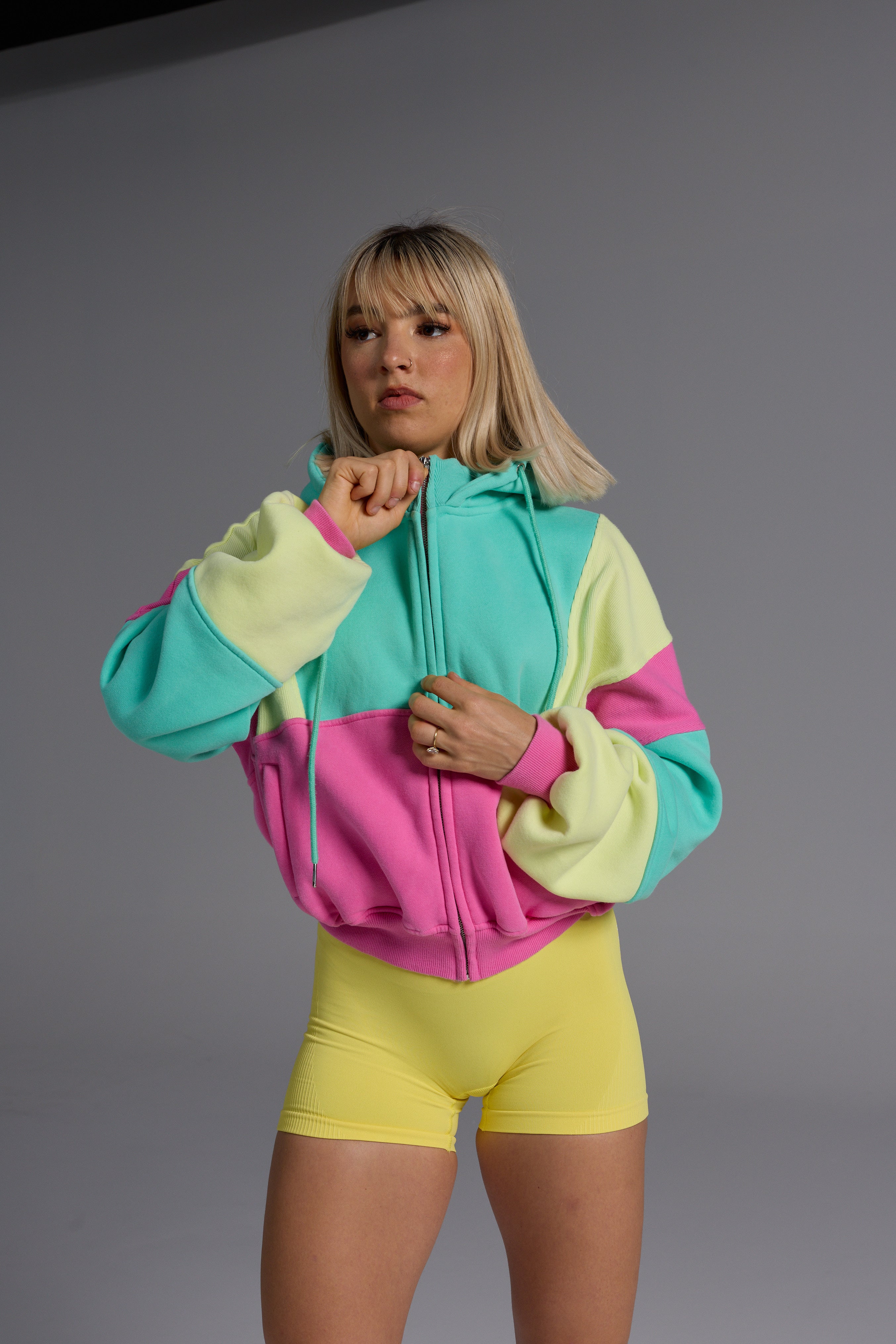 Woman wearing colourful oversized cropped fleece and yellow gym shorts from Peppamint activewear