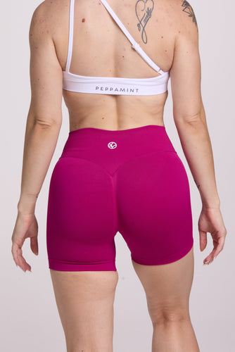 Front cross over strap activewear bra in seamless fabric with adjustable back straps, and ribbed supportive underbust band in white and seamless gym tights with booty contouring panels, invisible scrunch technology, sweetheart shaped back seams and thick supportive fabric in magenta pink