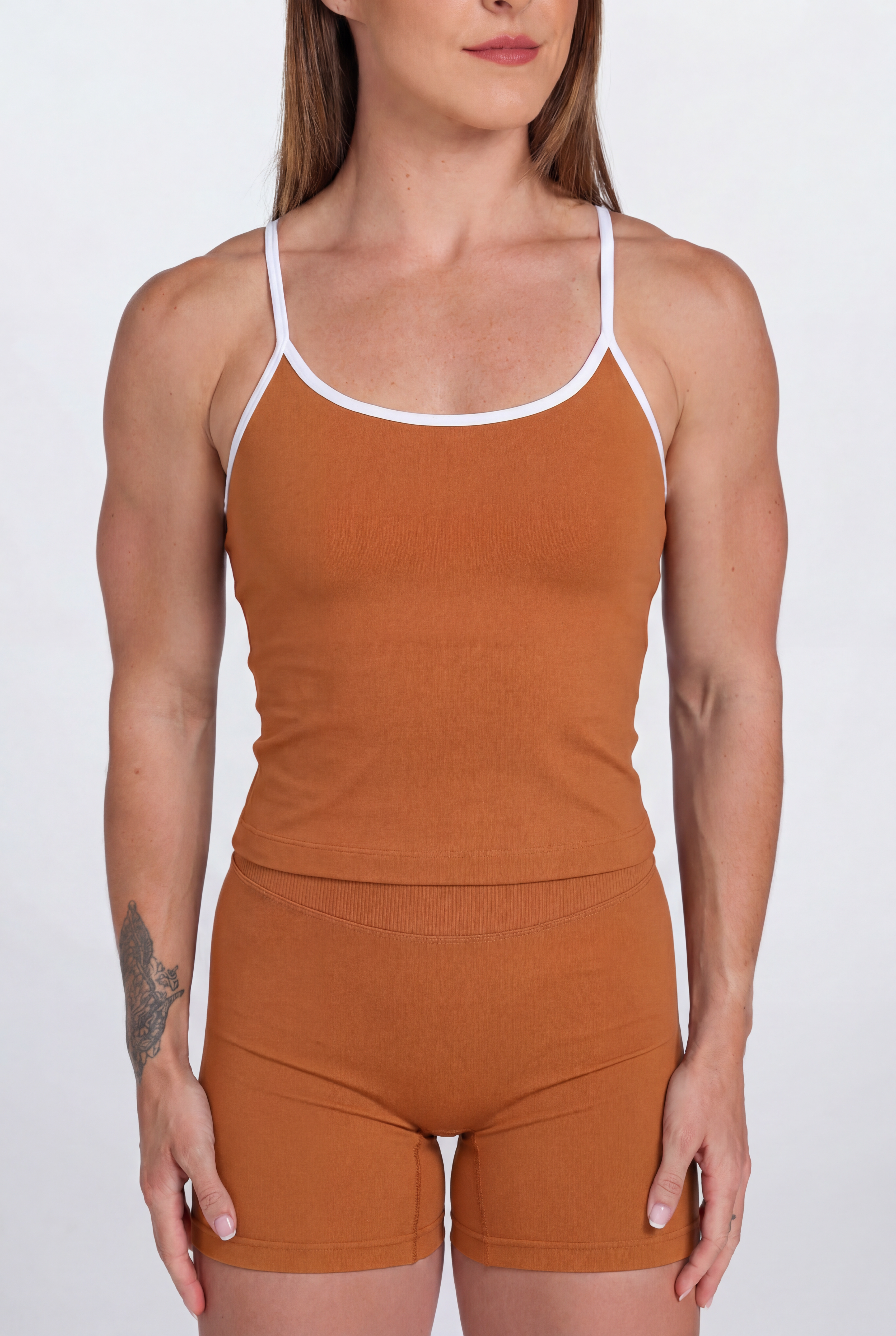 Woman wearing a Burnt Orange tank top and shorts set with white trim on a white background