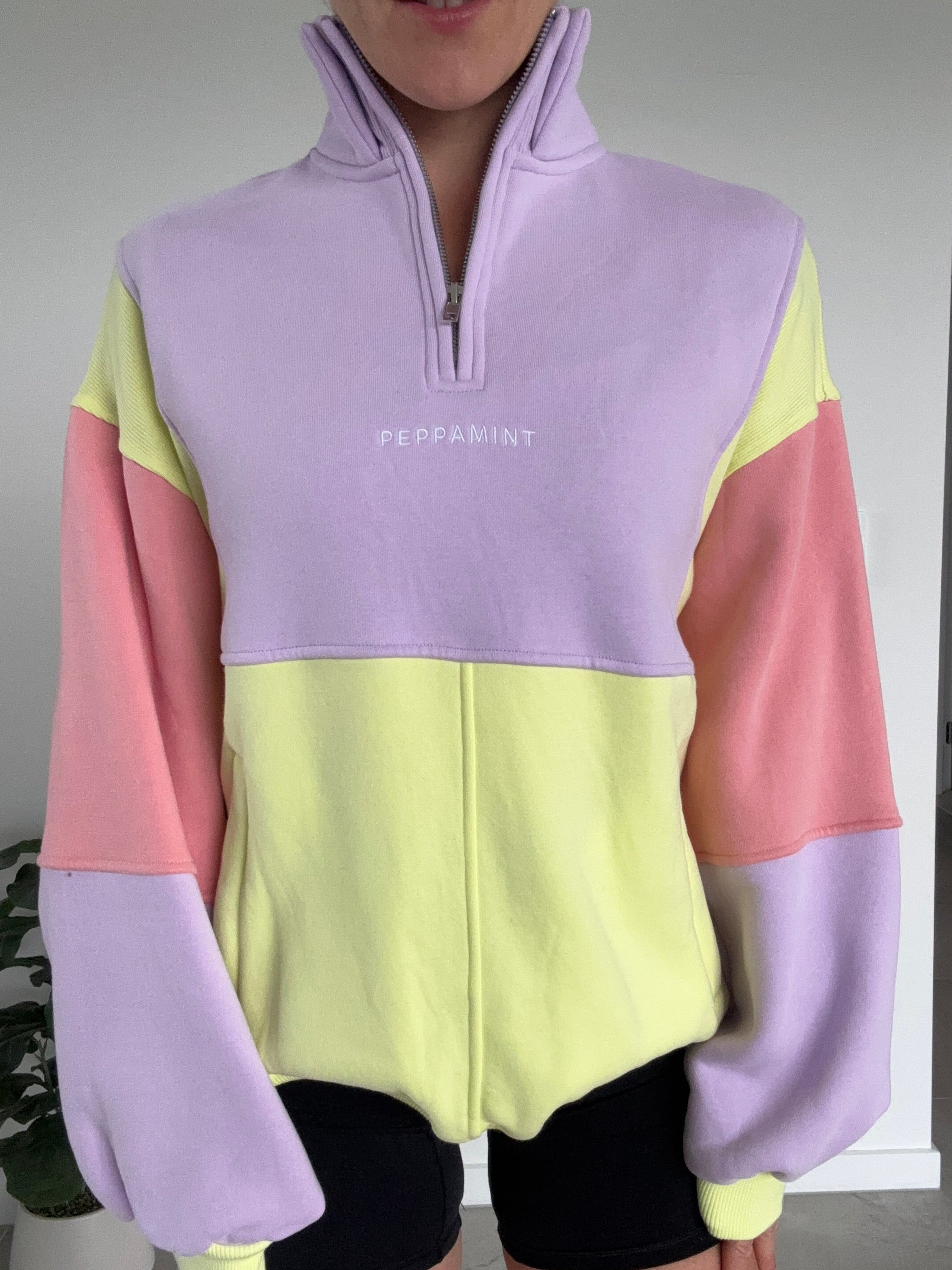 Color-blocked hoodie with pink, yellow, and purple sections on a white surface.