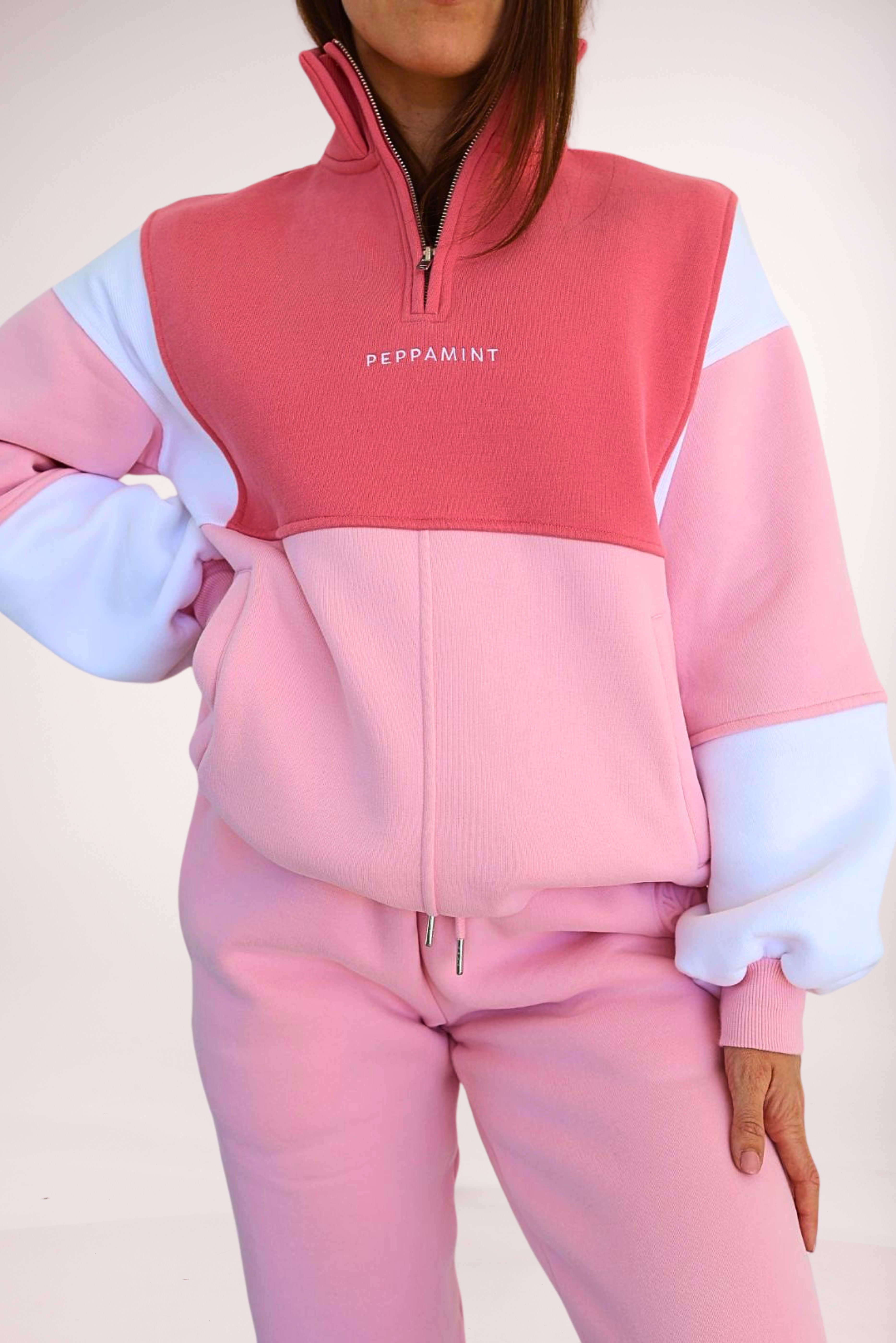 1/4 zip fleece jumper with double collar, in peony pink/white and baby pink colour panels, with feature panels ribbed stretchy fabric inserts, and two convenient zip pockets paired with fleece lined joggers with elasticated waistband, drawstring and embossed logo icon on pocket