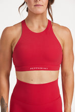 Load image into Gallery viewer, Buttery soft high neck women&#39;s sports bra with a supportive elasticated hem and triple layered fabric with removable pads for extra support and crossover back straps in Raspberry red.
