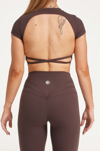 Buttery soft high waisted women's gym tights with curved hem stitched detailing for a butt shaping effect, and no front rise seam, paired with an open back women's crop t-shirt with a supportive elasticated hem and triple layered fabric with removable pads for extra support and aesthetic cross back straps in dark chocolate.