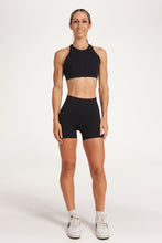 Load image into Gallery viewer, Buttery soft high waisted women&#39;s gym shorts with 4&quot; inseam with curved stitched detailing for a butt shaping effect, and no front rise seam, paired with a high neck women&#39;s sports bra with a supportive elasticated hem and triple layered fabric with removable pads for extra support and crossover back straps in Black.
