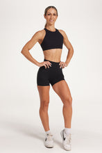 Load image into Gallery viewer, Buttery soft high waisted women&#39;s gym shorts with 4&quot; inseam with curved stitched detailing for a butt shaping effect, and no front rise seam, paired with a high neck women&#39;s sports bra with a supportive elasticated hem and triple layered fabric with removable pads for extra support and crossover back straps in Black.
