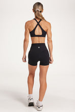 Load image into Gallery viewer, Buttery soft high waisted women&#39;s gym shorts with 4&quot; inseam with curved stitched detailing for a butt shaping effect, and no front rise seam, paired with a high neck women&#39;s sports bra with a supportive elasticated hem and triple layered fabric with removable pads for extra support and crossover back straps in Black.
