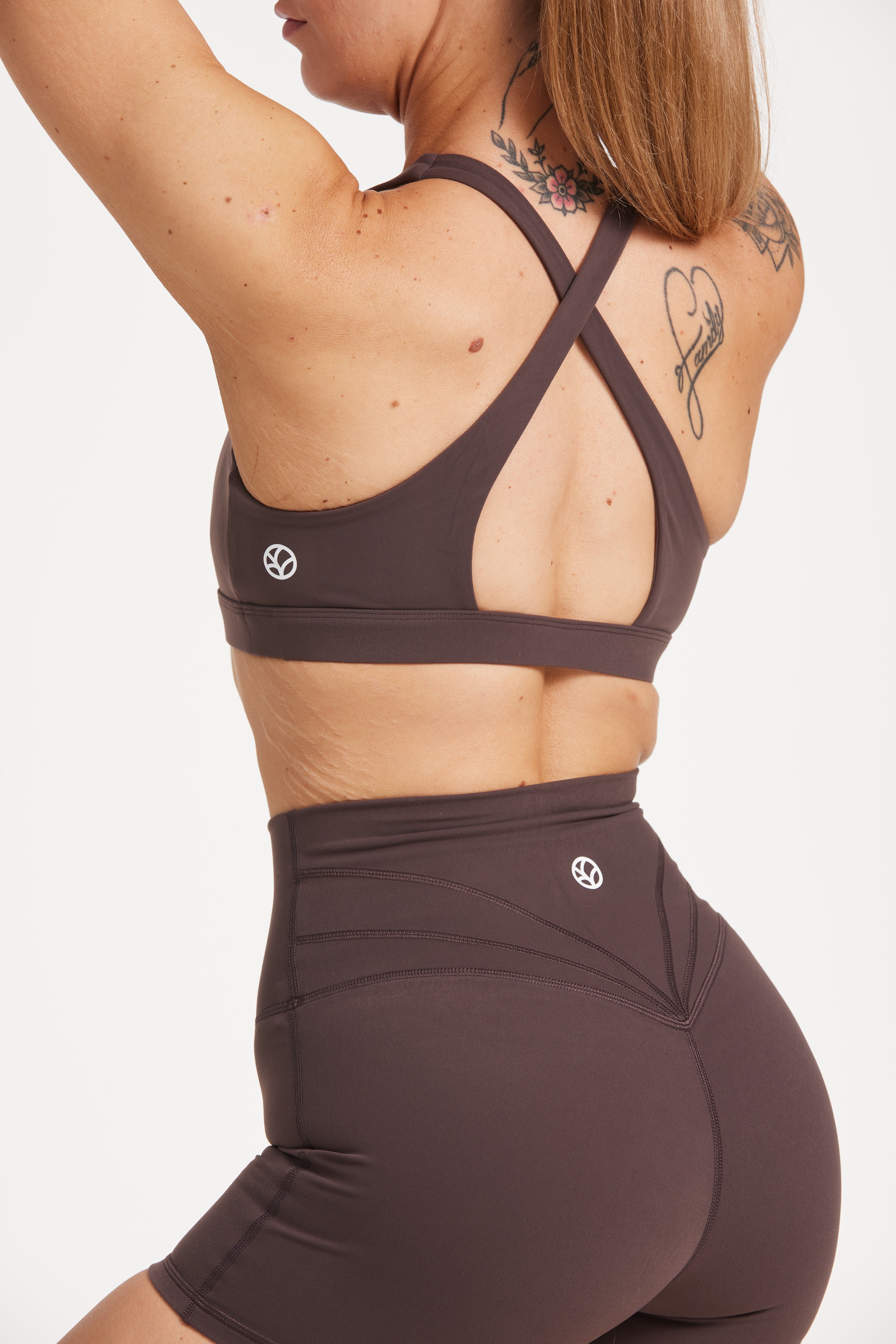 Buttery soft high waisted women's gym shorts with 4" inseam with curved stitched detailing for a butt shaping effect, and no front rise seam, paired with a high neck women's sports bra with a supportive elasticated hem and triple layered fabric with removable pads for extra support and crossover back straps in Dark Chocolate.